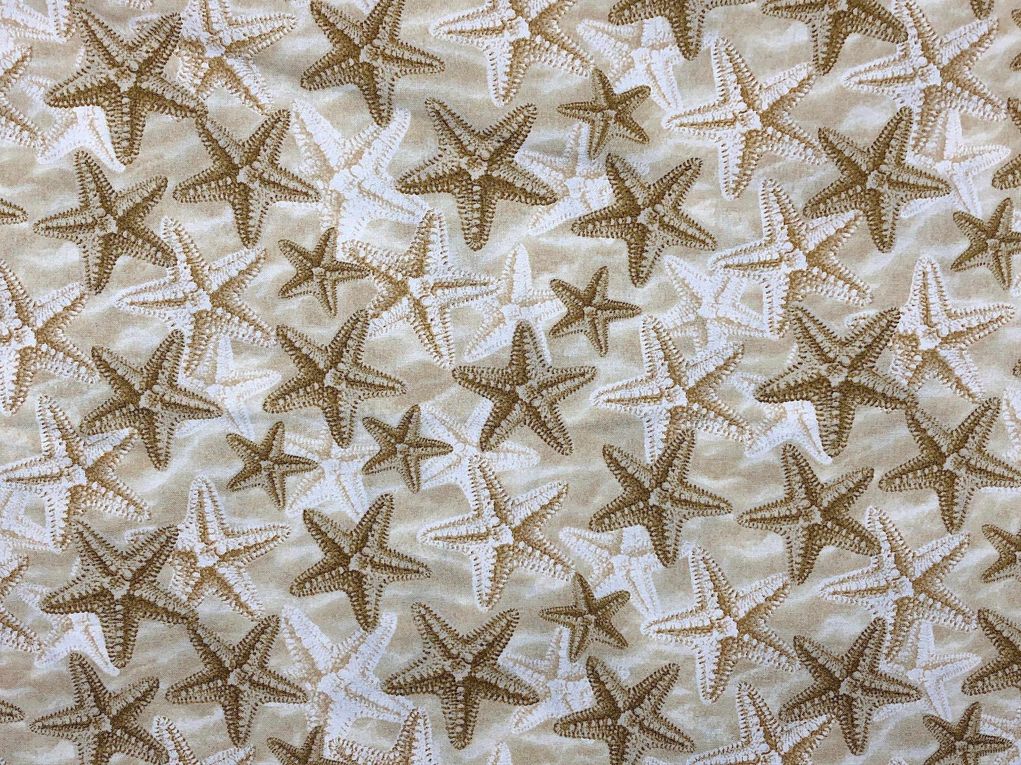 This fabric is covered with starfish on a sand background