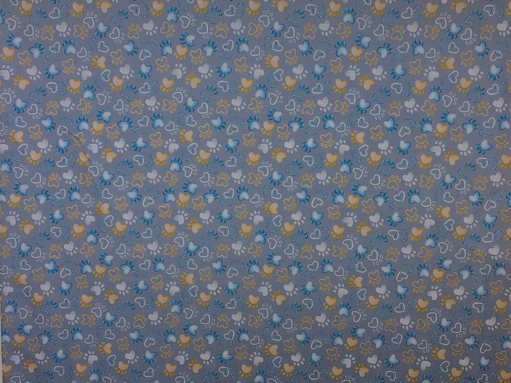 White, Blue and yellow paw prints and hearts cover this grey fabric. This fabric is part of the Think Pawsitive Collection designed by Andi Metz