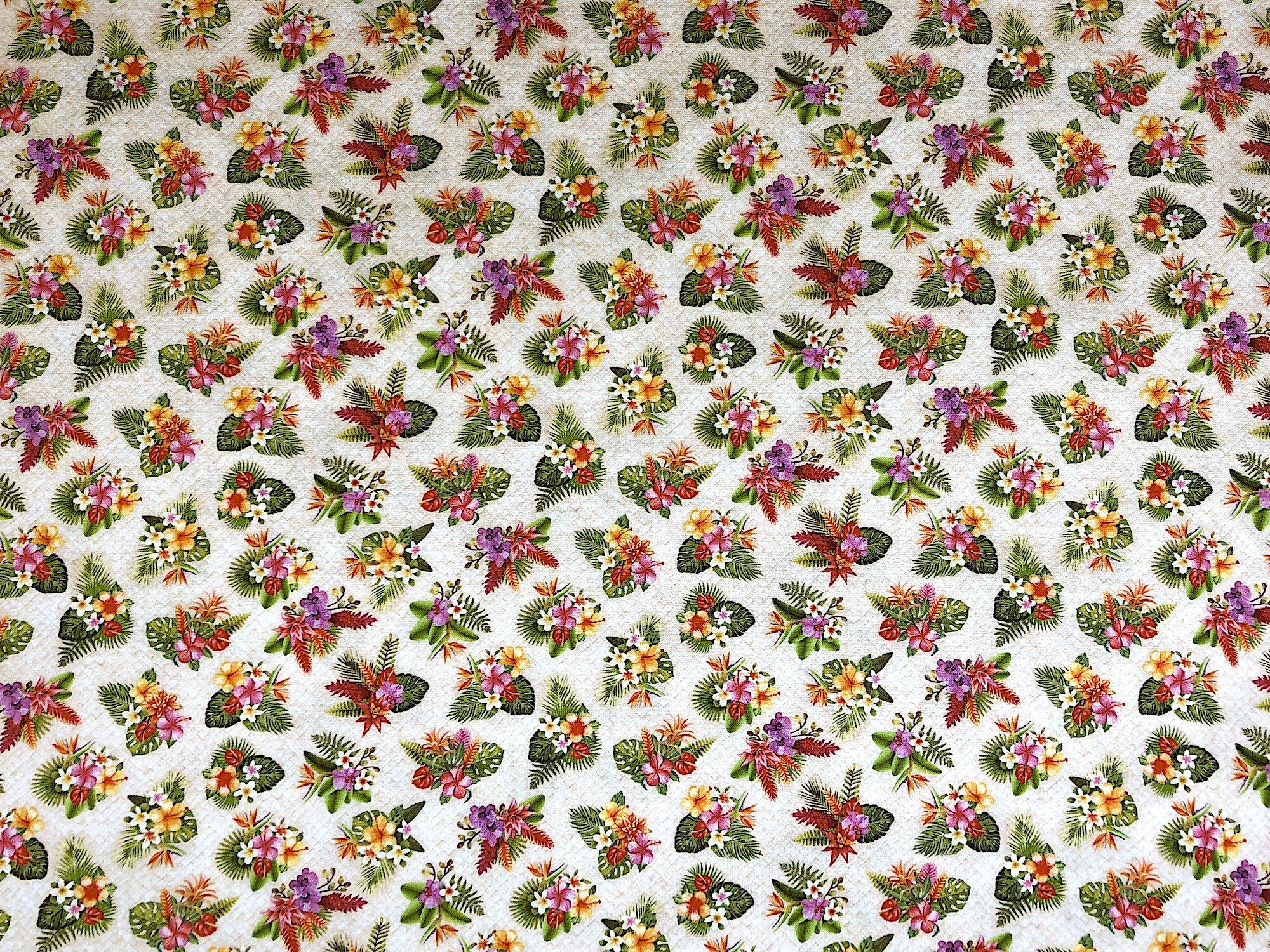 This fabric is a pretty tropical floral print with a light beige background. There are small flowers in groupings along with ferns and leaves.