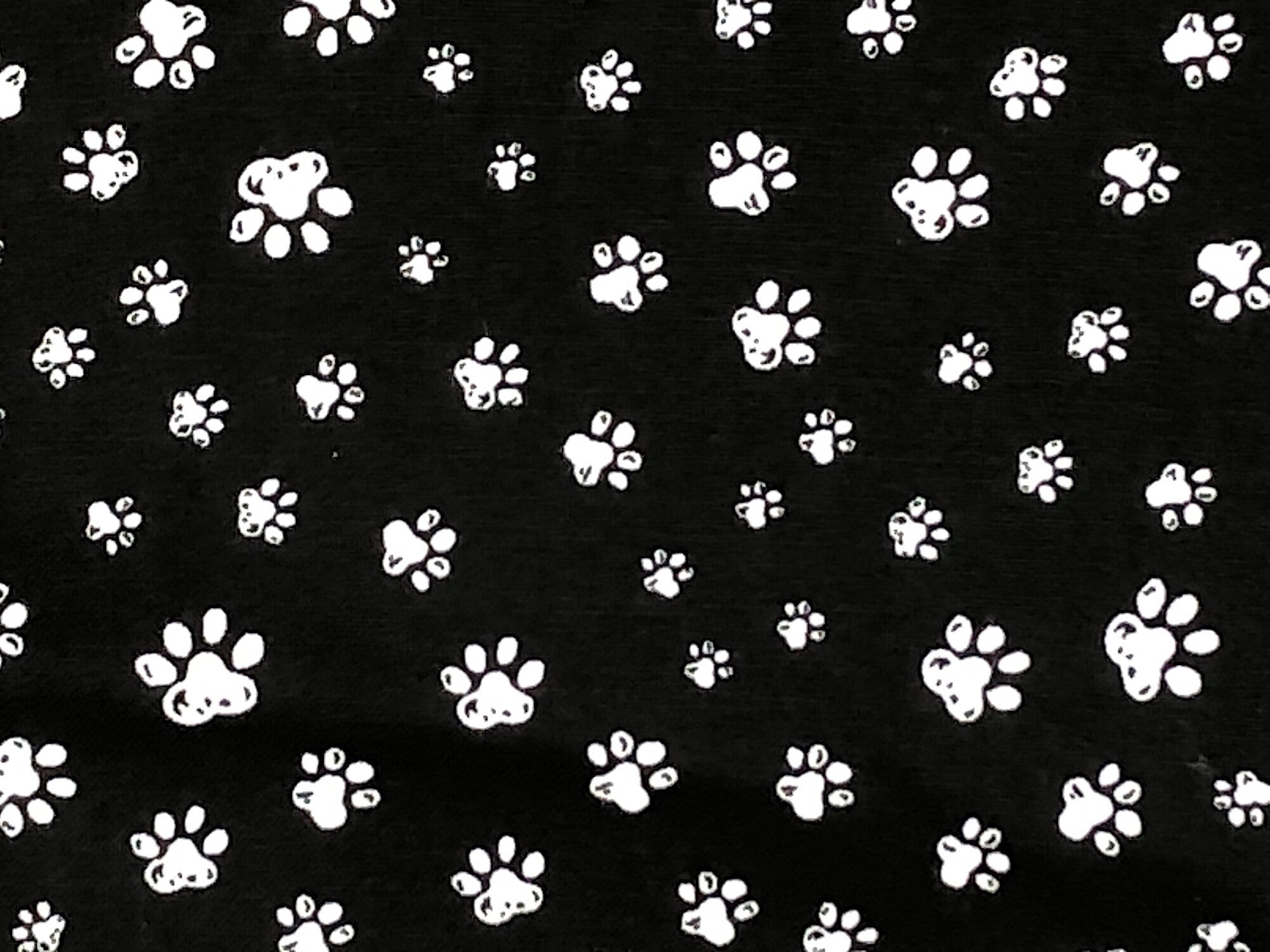 This fabric is a cute White Paw print design on a Black background.