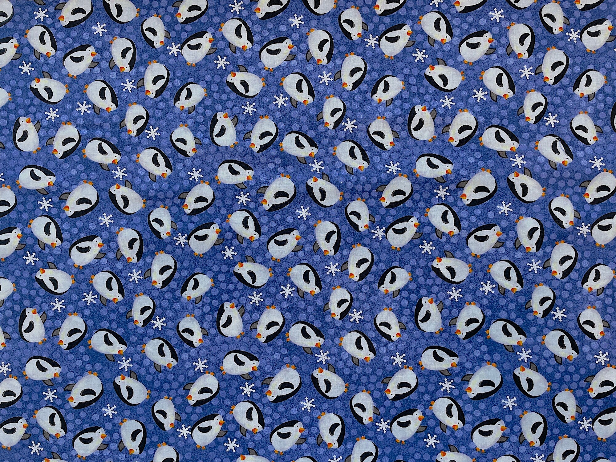 Black and white penguins cover this blue fabric by Clothworks