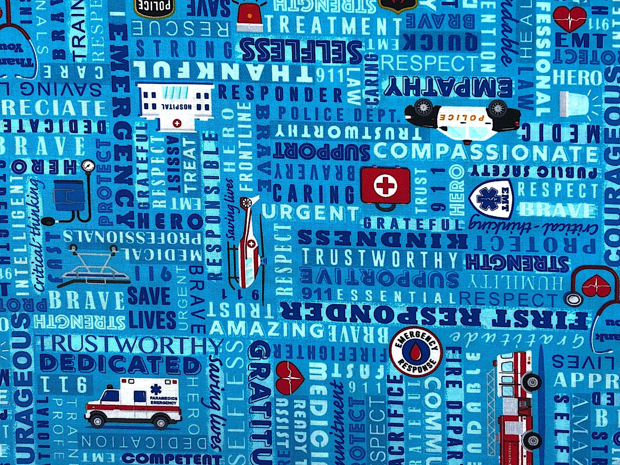 Blue cotton fabric covered with police cars, ambulances and sayings such as trustworthy, strength, respect and more.