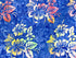 This fabric is covered with hibiscus. The flowers have shades of yellow, pink, blue and green. The background has shades of blue.