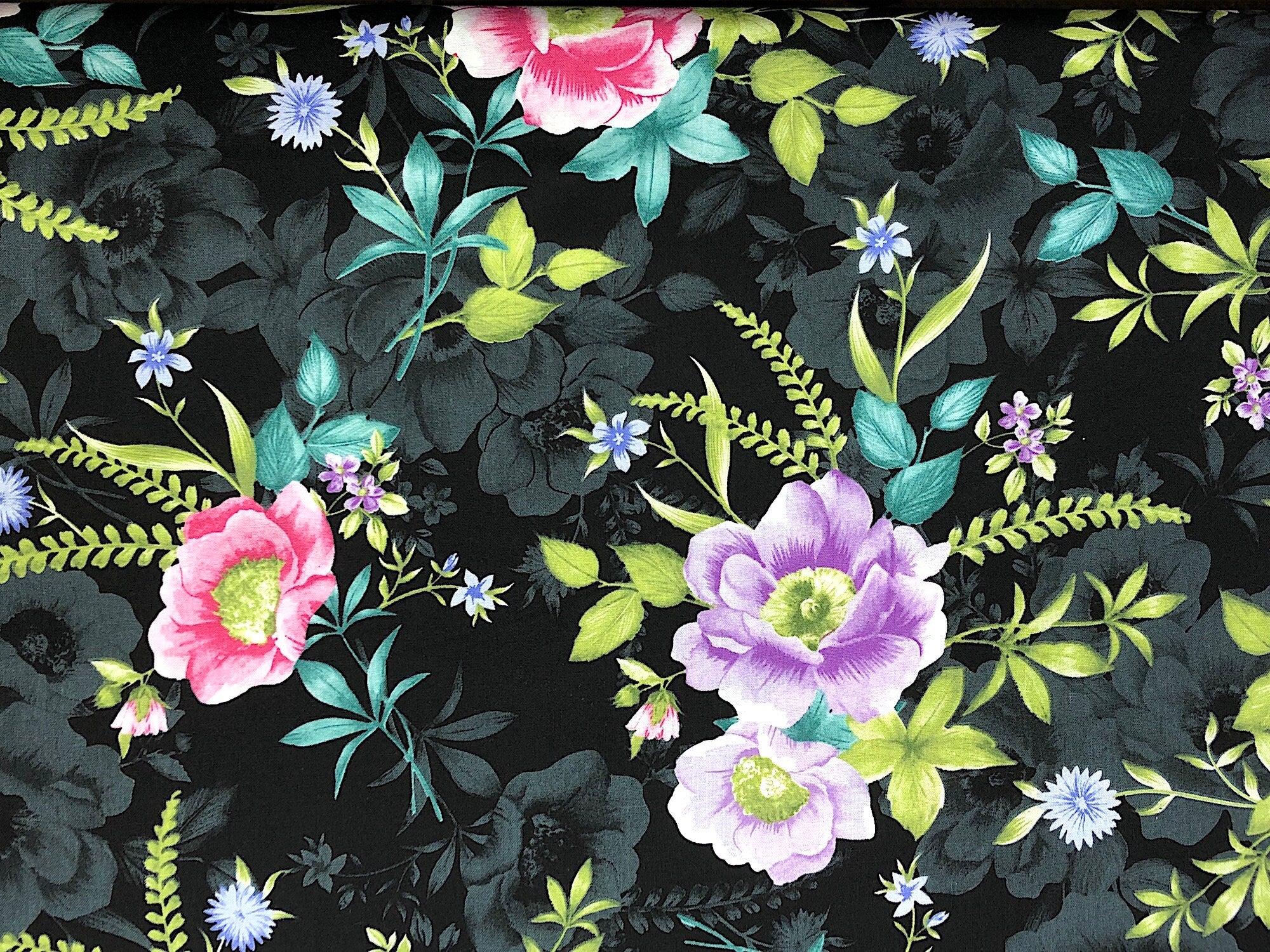 Black cotton fabric covered with pink and purple flowers.