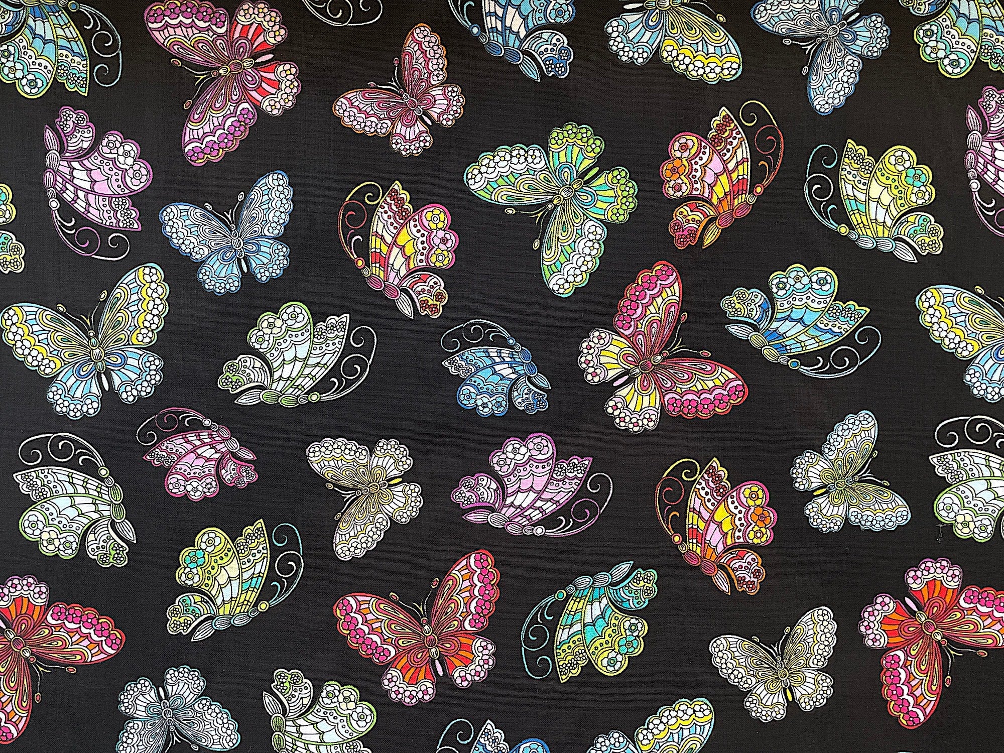 Green, yellow, blue, pink, orange and yellow butterflies cover this black fabric. This fabric is part of the Dazzling Garden Collection by Kanvas Studio