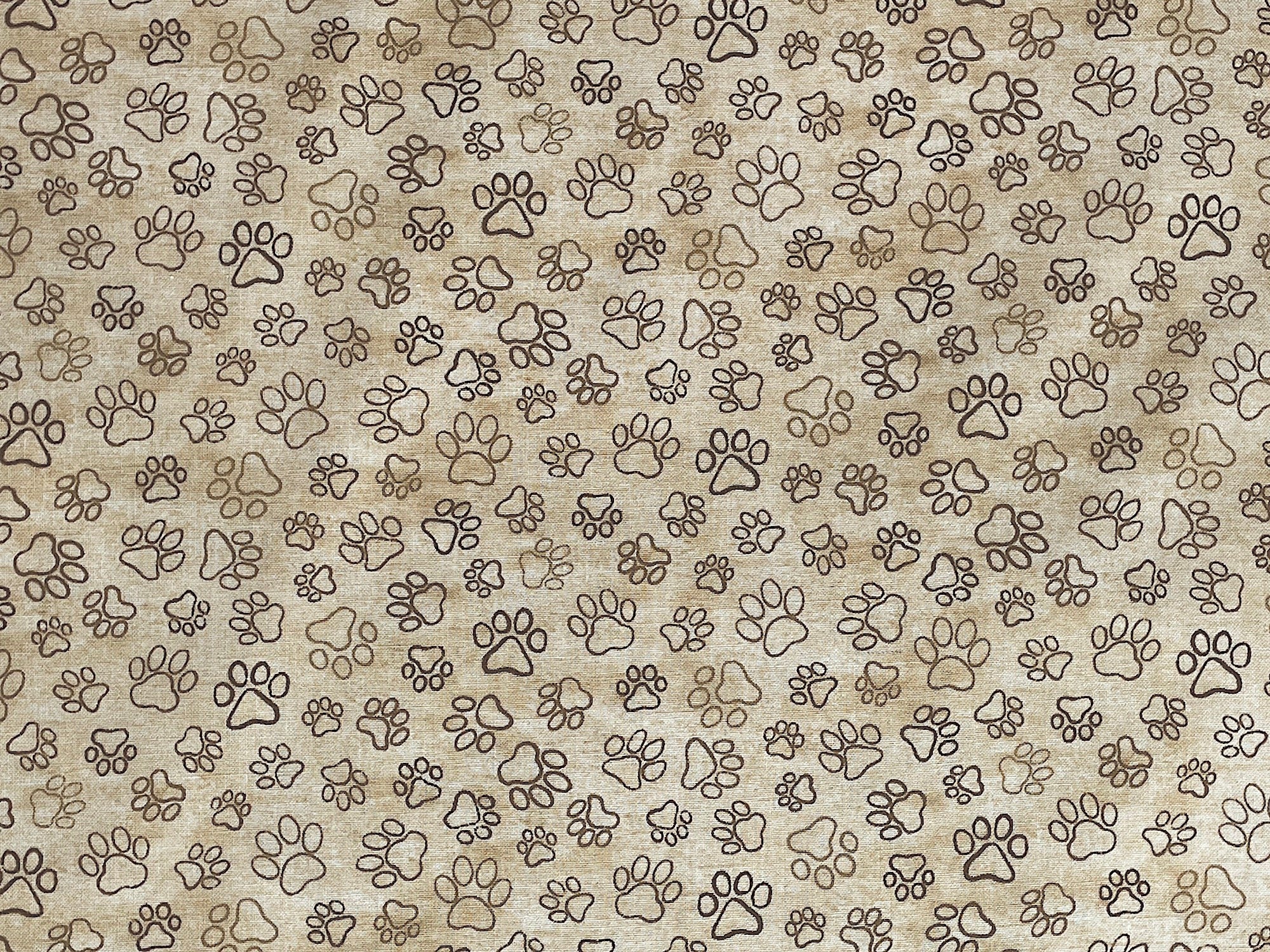 This cream colored fabric is covered with light tan and brown paw prints