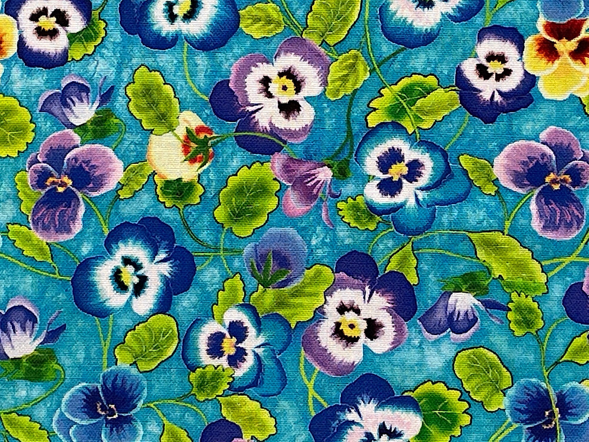 Close up of teal fabric covered with yellow, blue and purple pansies and green leaves.