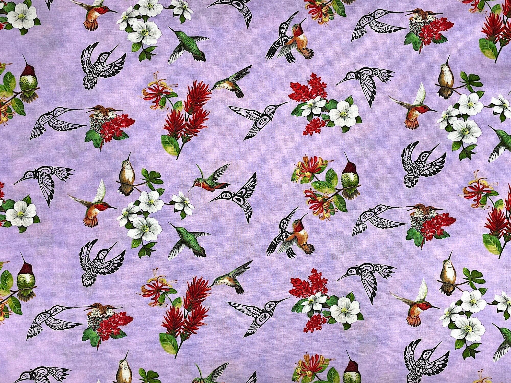 Lavender cotton fabric covered with hummingbirds and flowers.