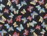This black fabric with gold specks is part of the Dazzling Garden Collection and is covered with butterflies. The butterflies are blue, red, and beige.