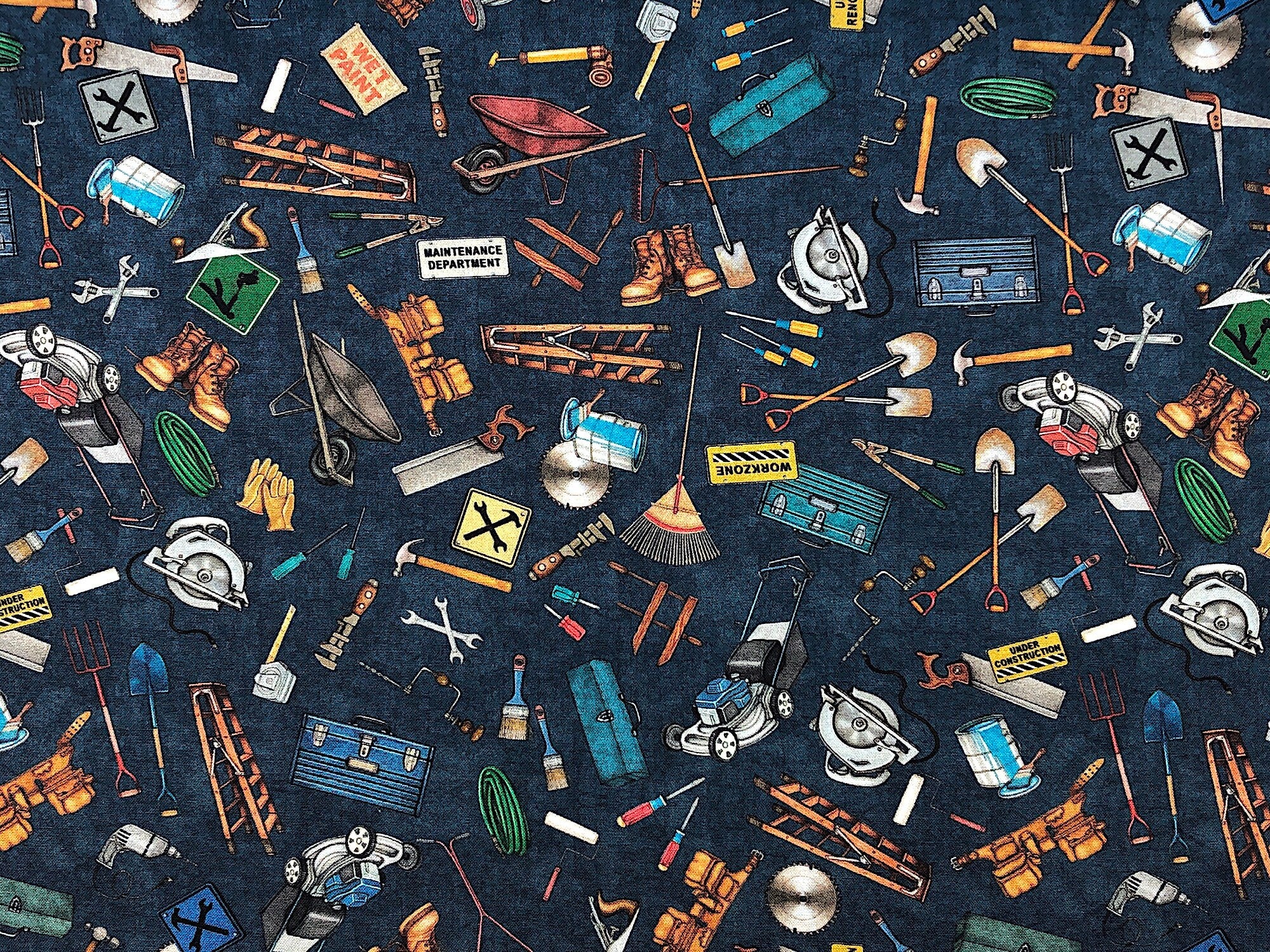This blue fabric is covered with lawnmowers, boots, hammers, saws, ladders, tool boxes, wheelbarrows and more.