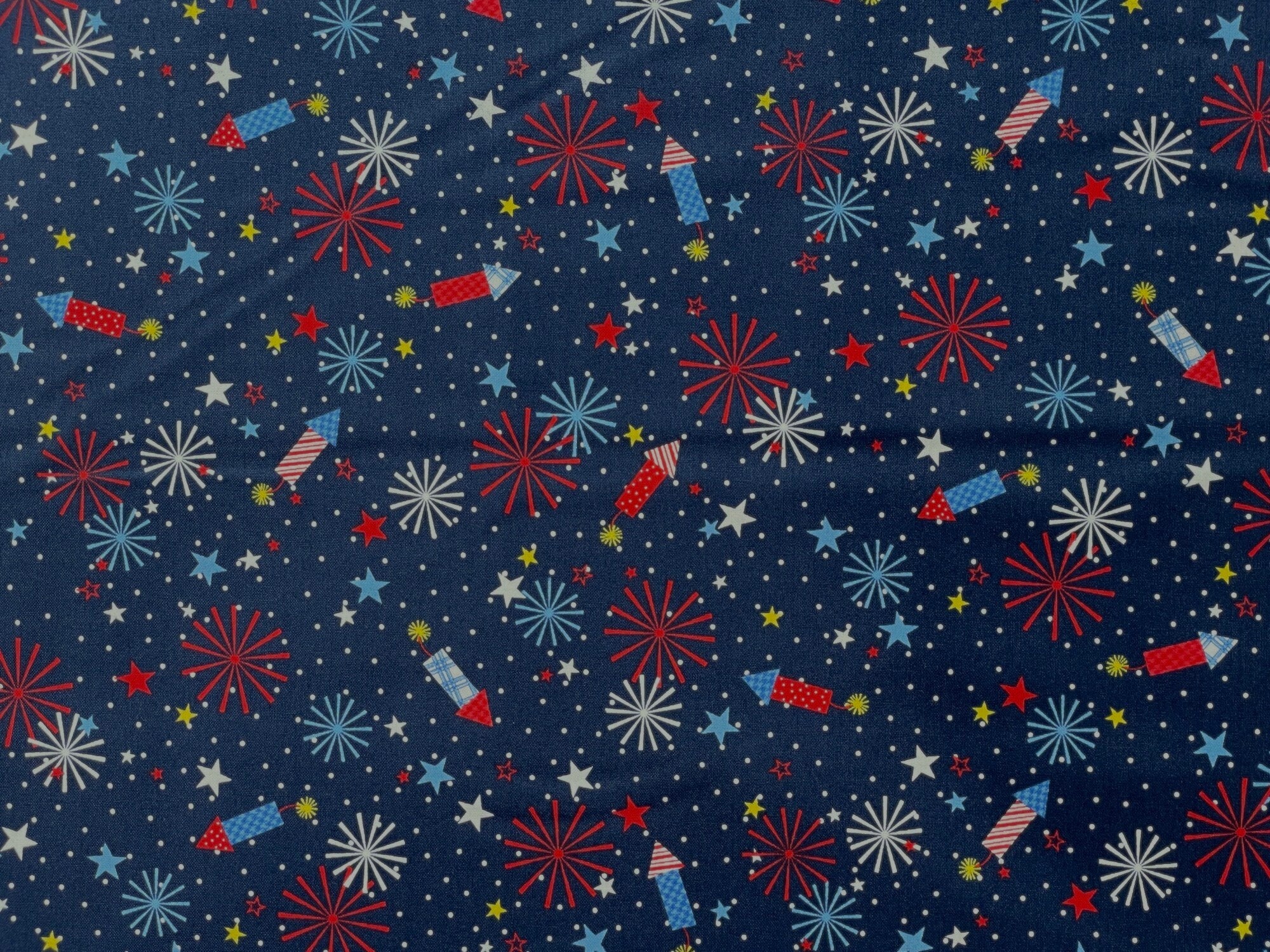 Here is a colorful Patriotic Fabric with Red White and Blue Fireworks on a Navy Blue background. You will also find yellow, red, blue and white stars and small white dots in the background. 