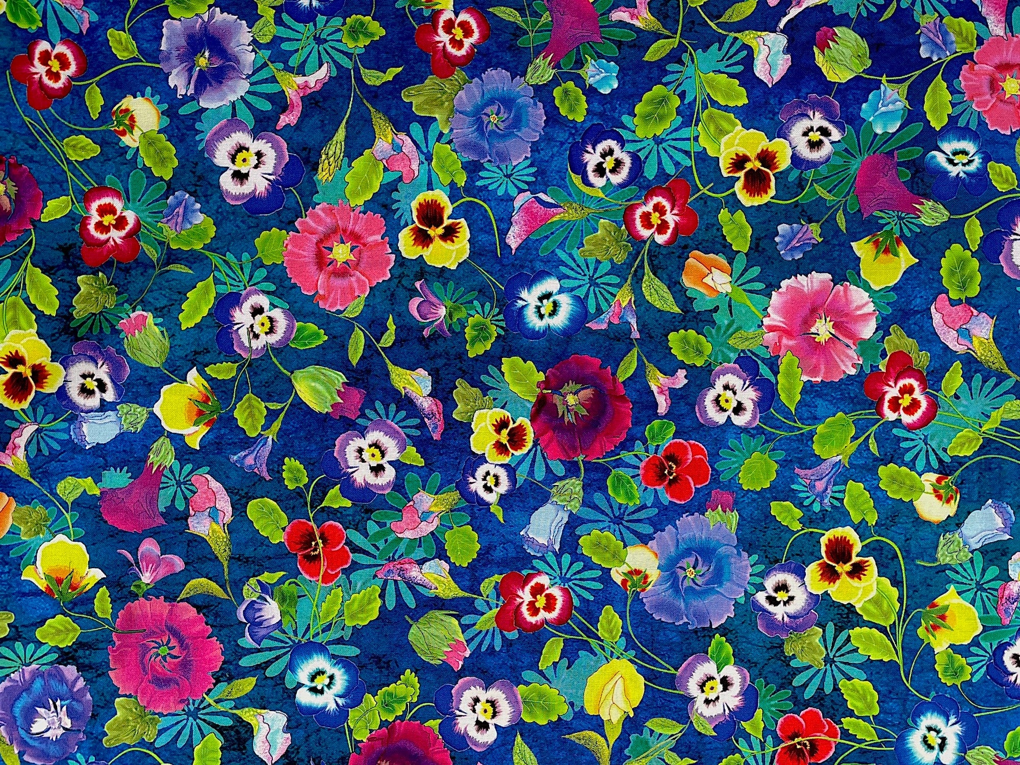 This blue fabric is covered with yellow, purple and red pansies. This fabric is part of the Garden Delight collection