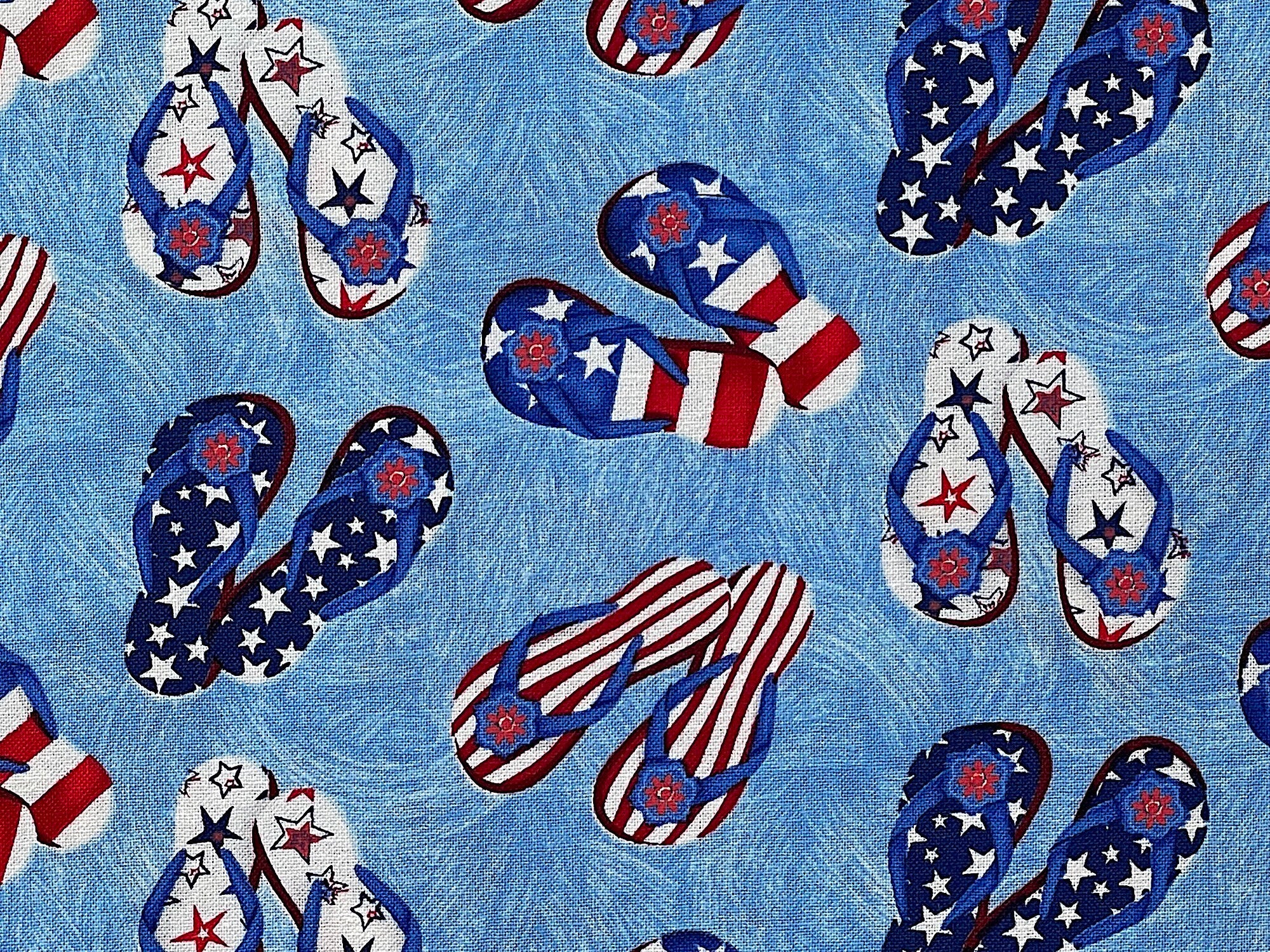Close up of red, white and blue flip flops on a blue background.