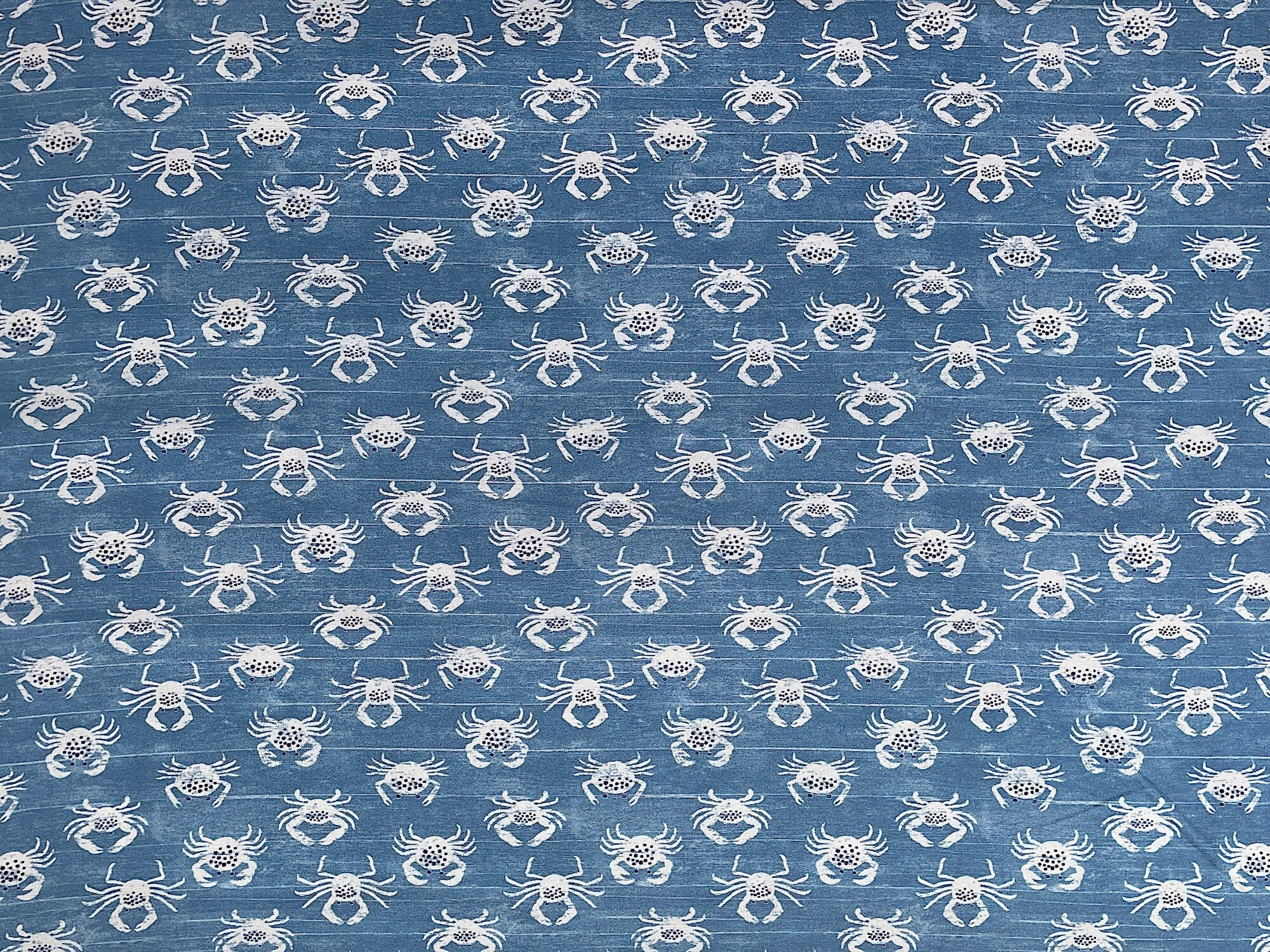 Blue cotton fabric covered with white crabs.