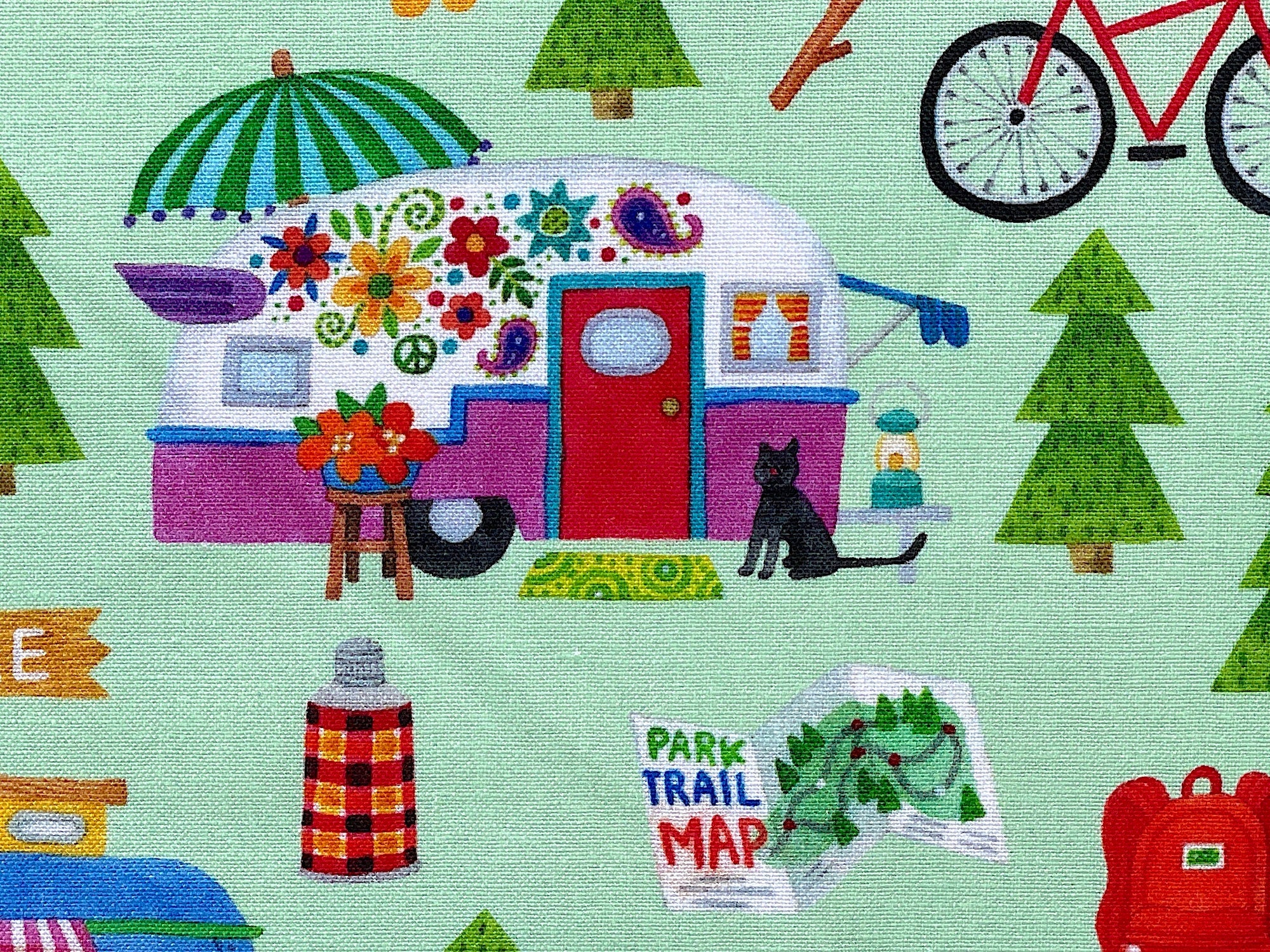 Close up of a travel trailer, cat, tree, park trail map and more.