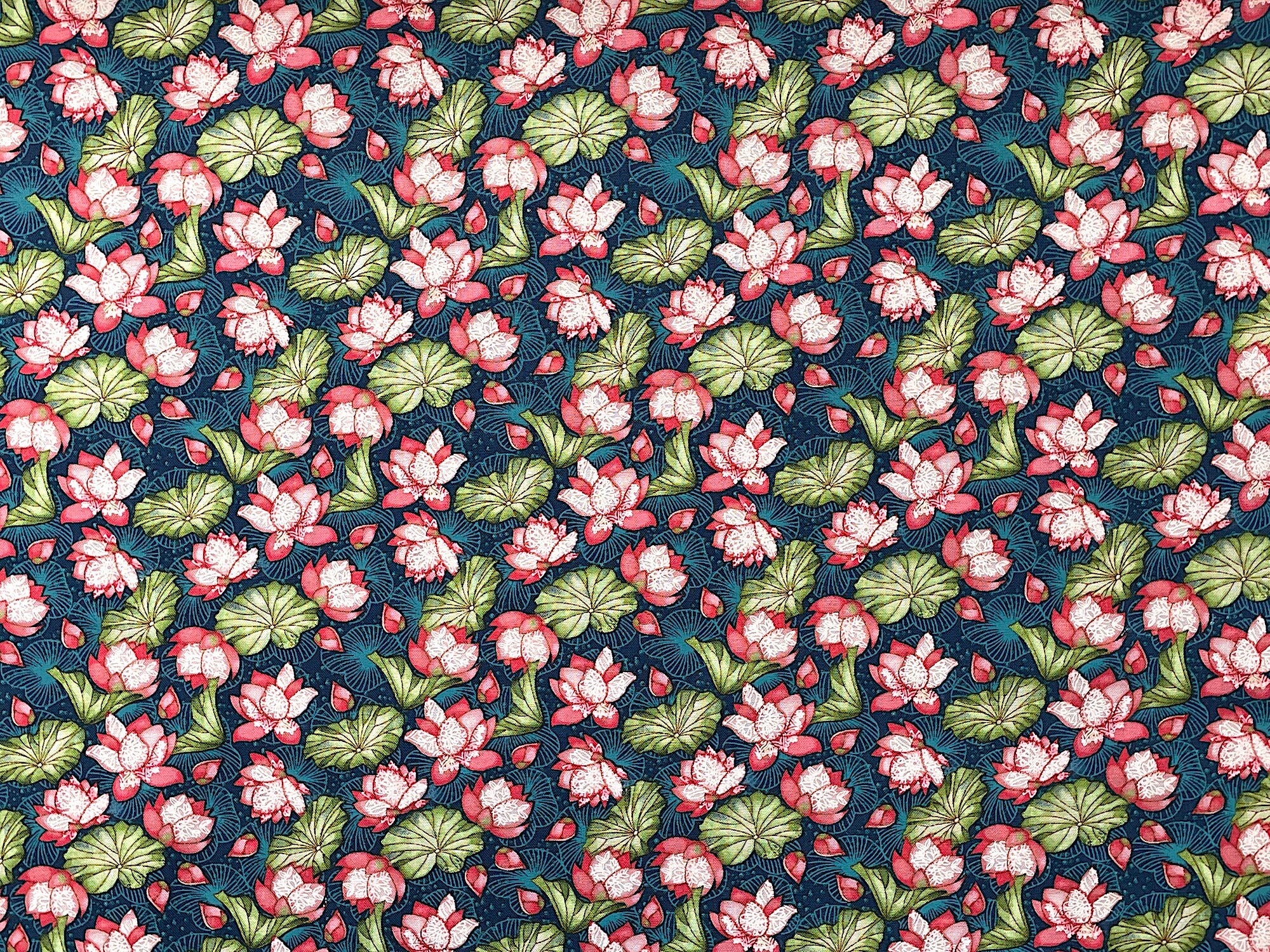This dark teal cotton fabric is covered with lily pads and water lilies. 
