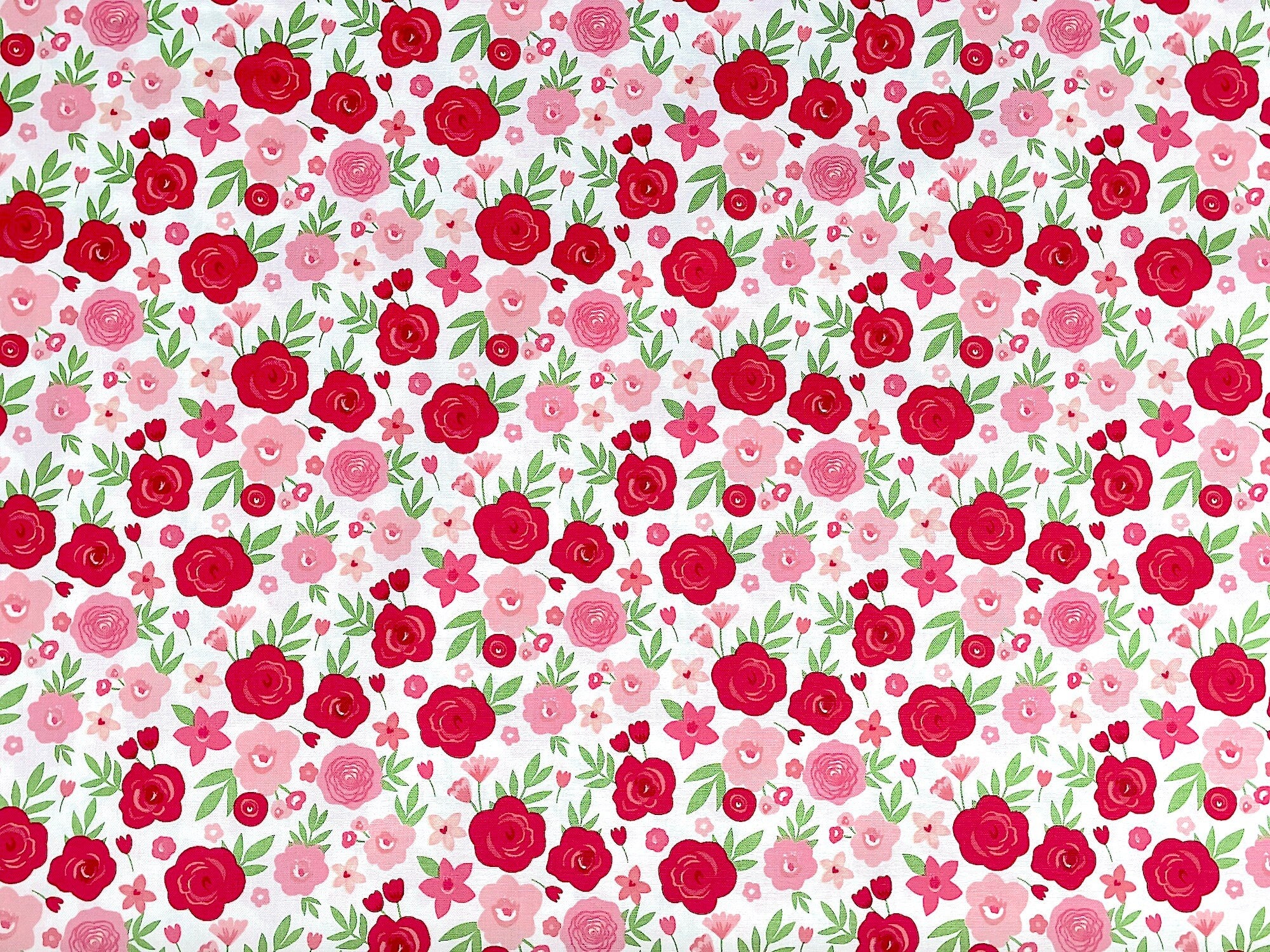 This fabric is covered with pink and red flowers on a white background.