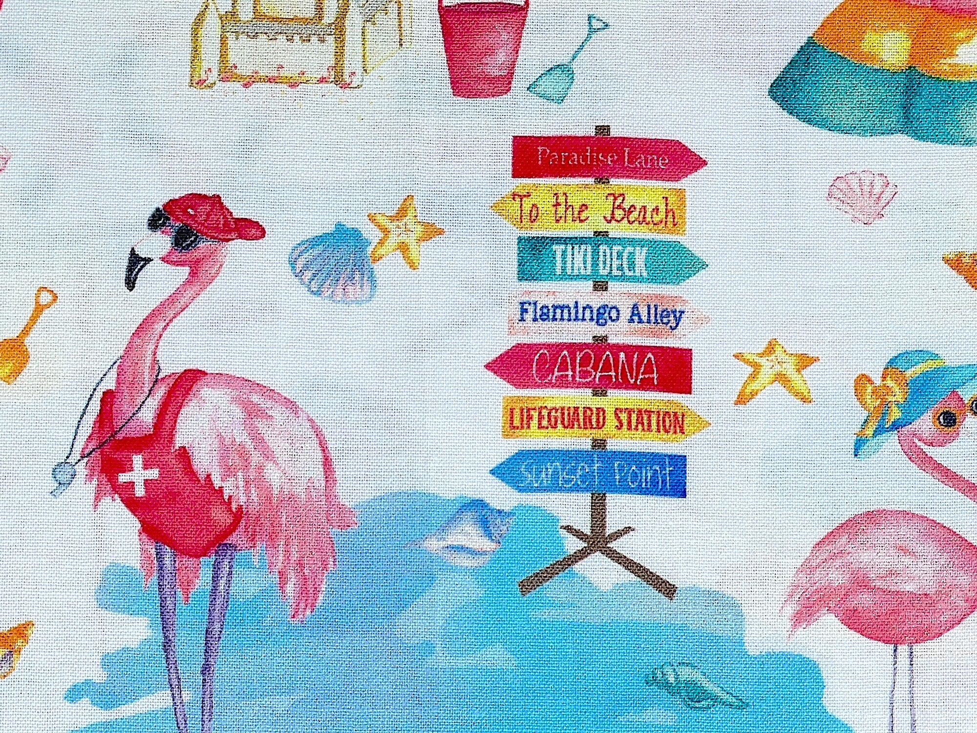 Close up of signs , shells, pink flamingo, sand pail and more.