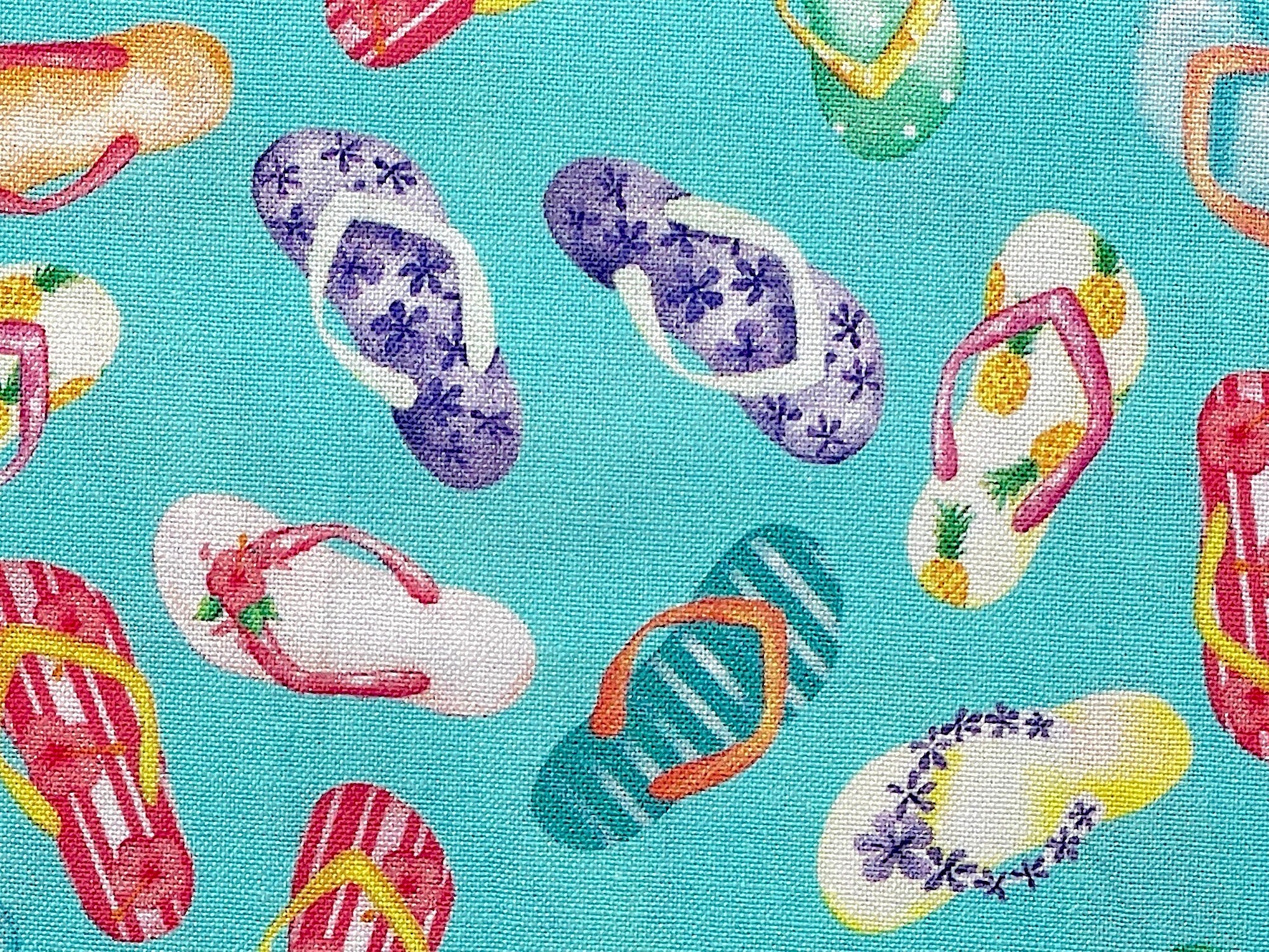 Close up of colorful flip flops on a turquoise background.