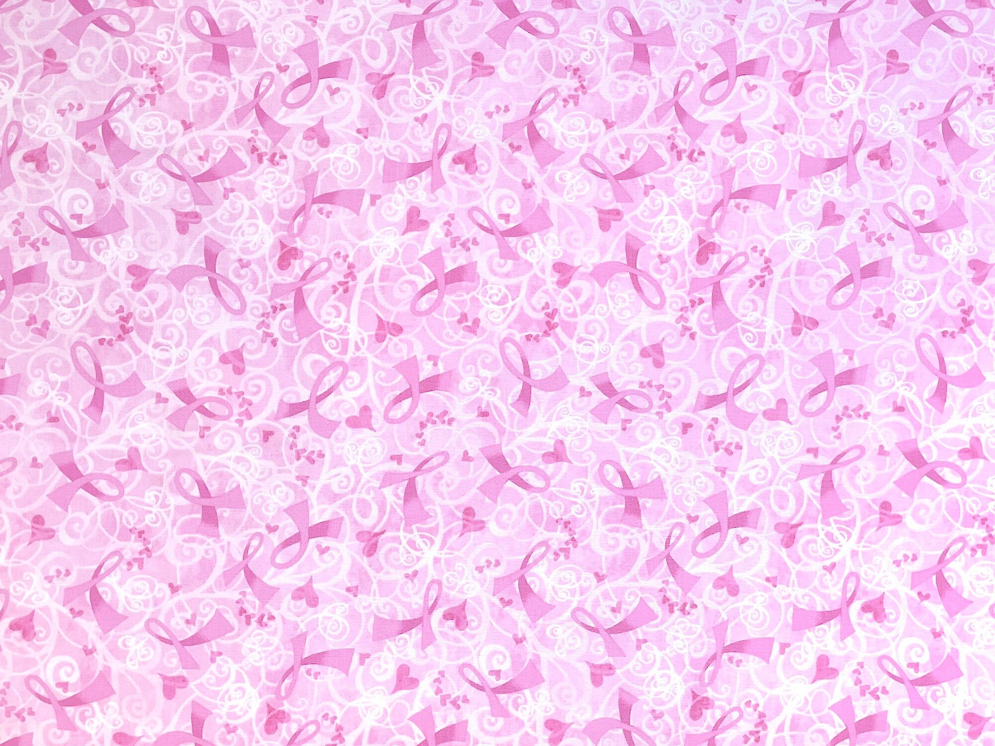 This pink awareness fabric is covered with pink ribbons and white scrolls.