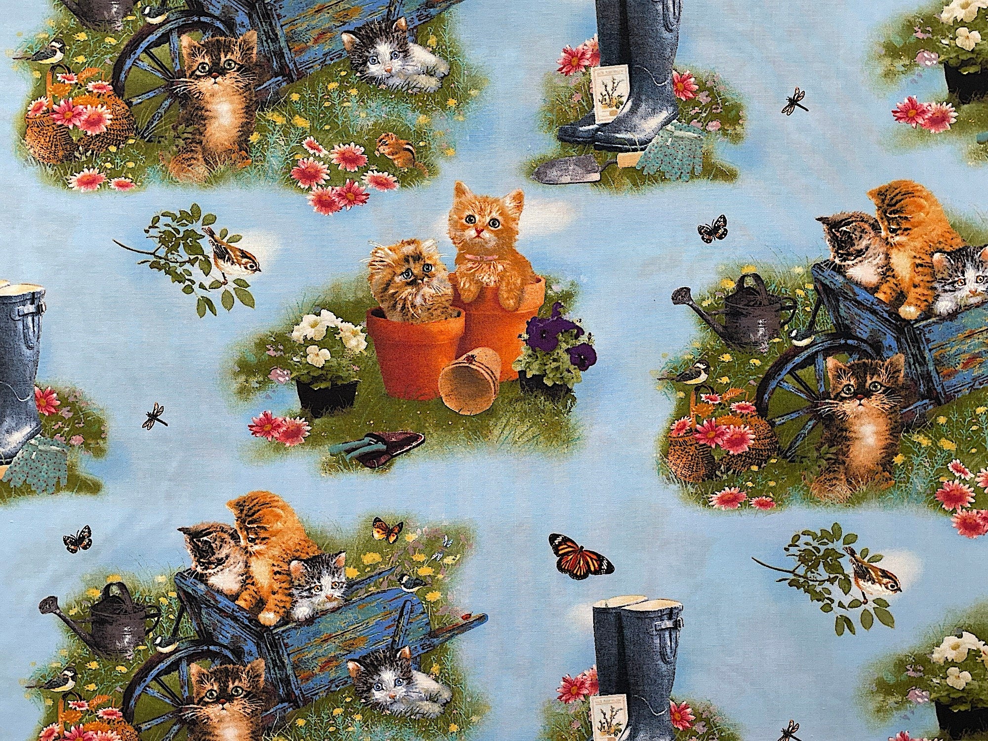 This blue fabric is covered with kittens in wheelbarrows and kittens sitting by pots