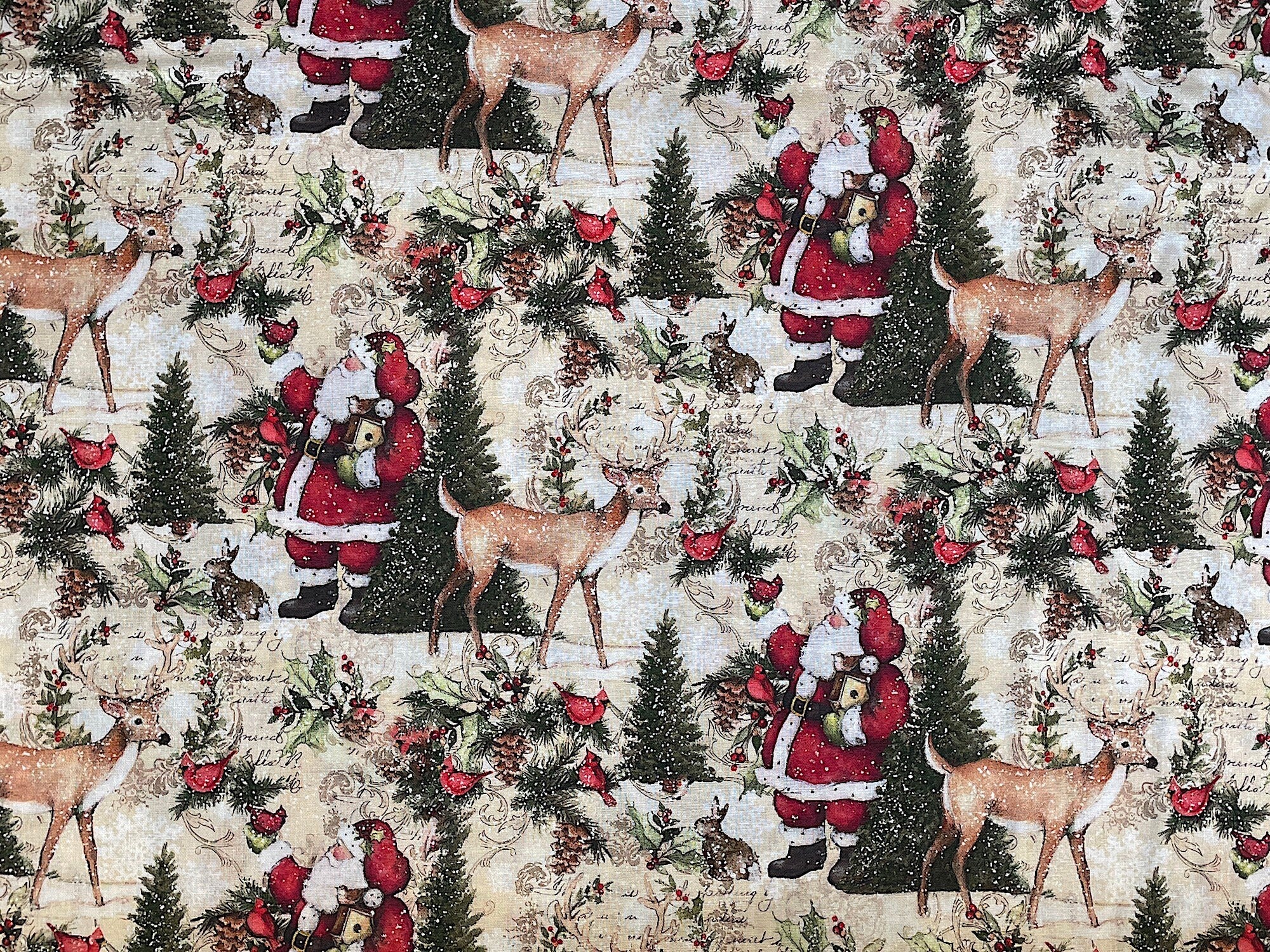 This beige cotton fabric features Santa Claus. Santa is standing next to an evergreen tree holding a cardinal. There are also deer and bunnies throughout the fabric.