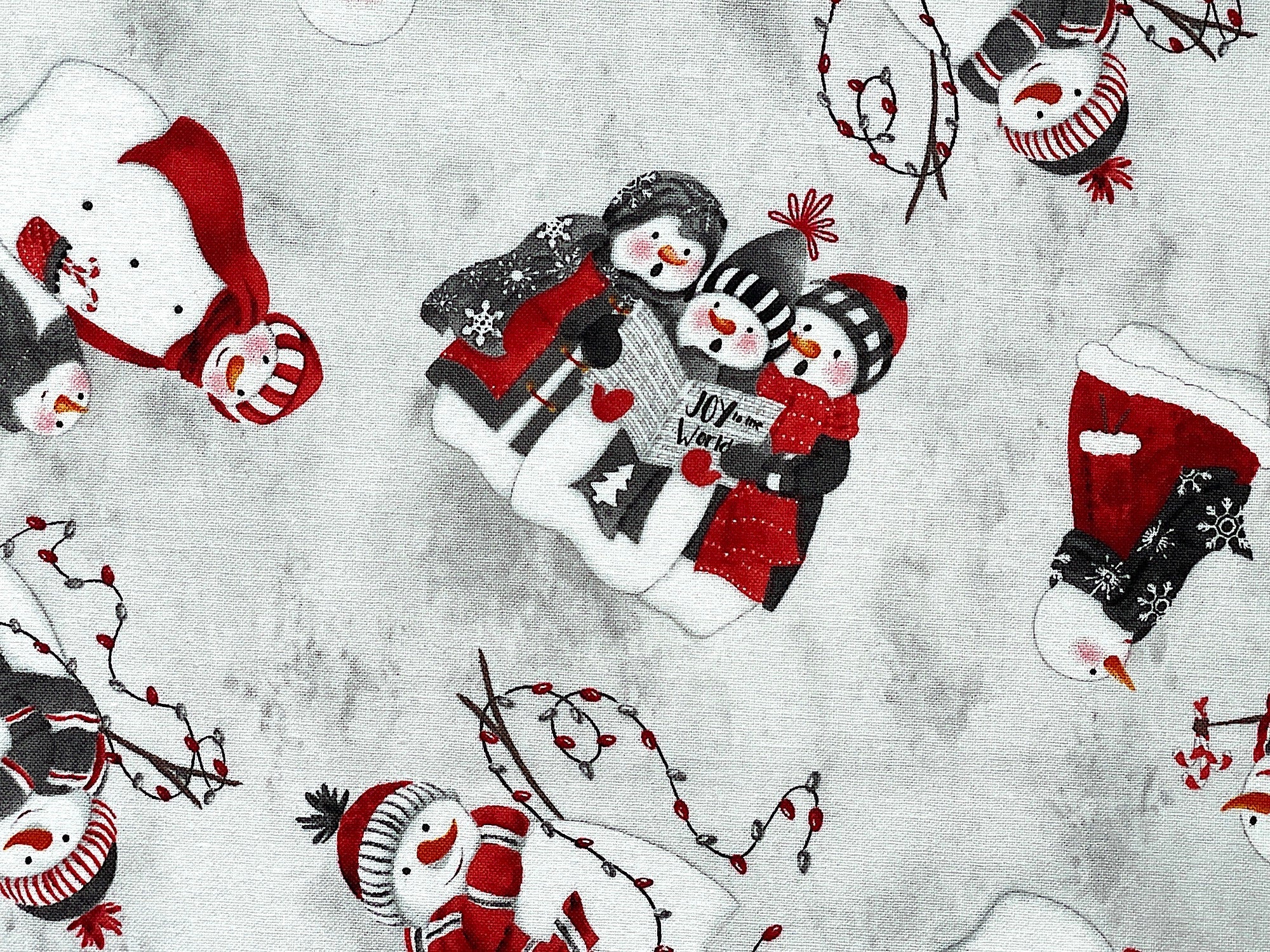 This fabric has a white and grey background and is covered with snowmen. Some of the snowmen have Christmas lights, some are singing and others are just standing.