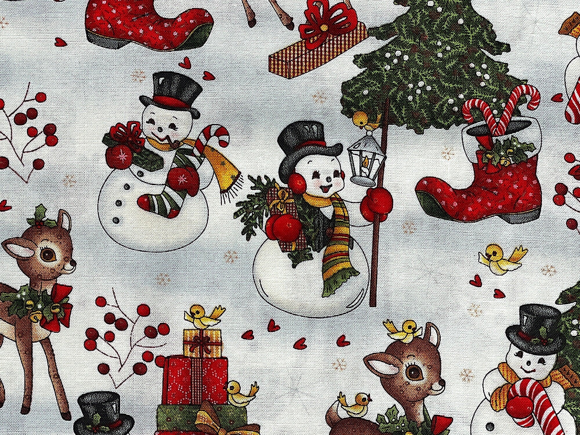 Close up of white cotton fabric covered with snowmen, reindeer and trees.