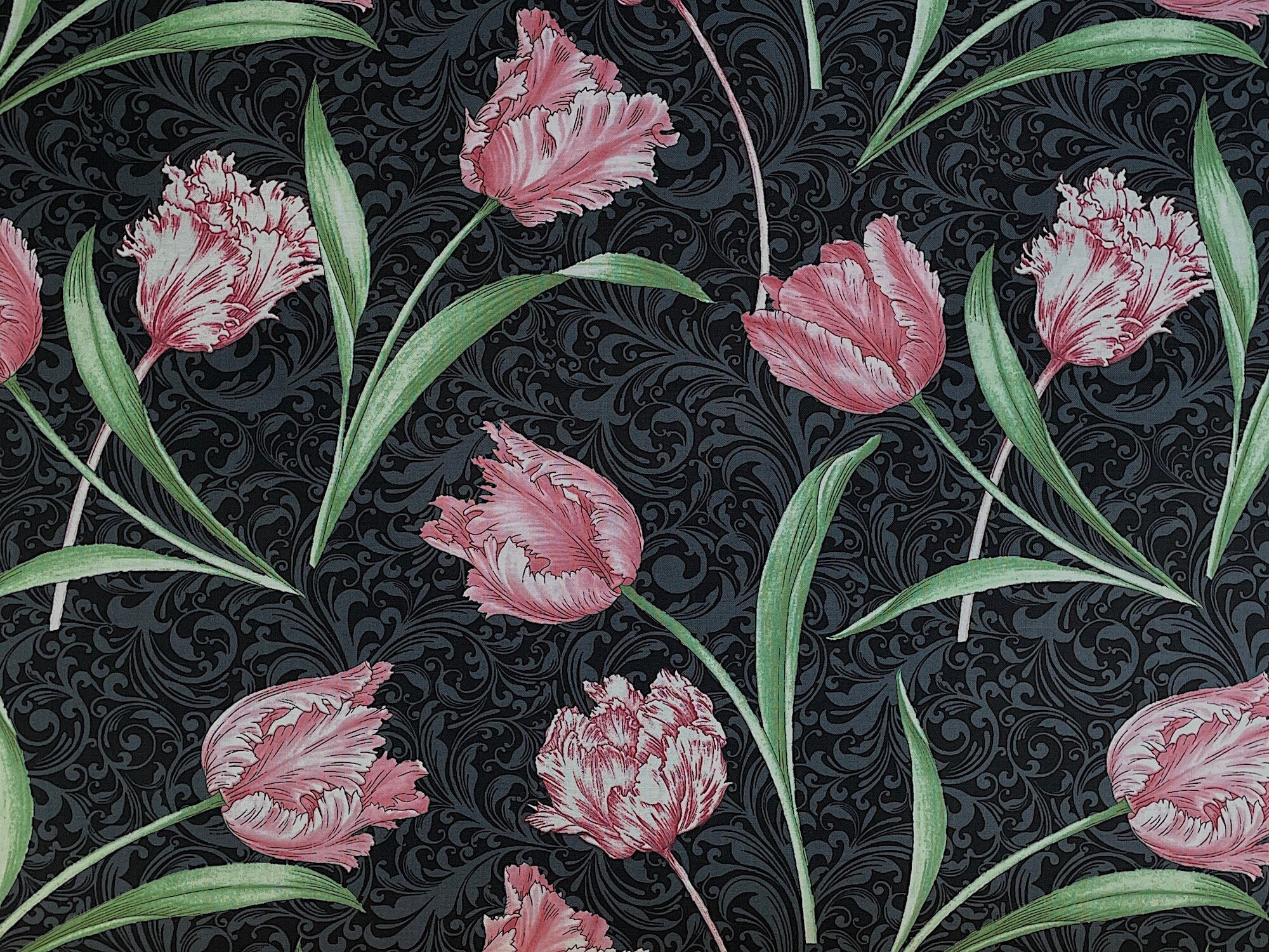 This black cotton fabric is covered with etched pink tulips and green stems and leaves.