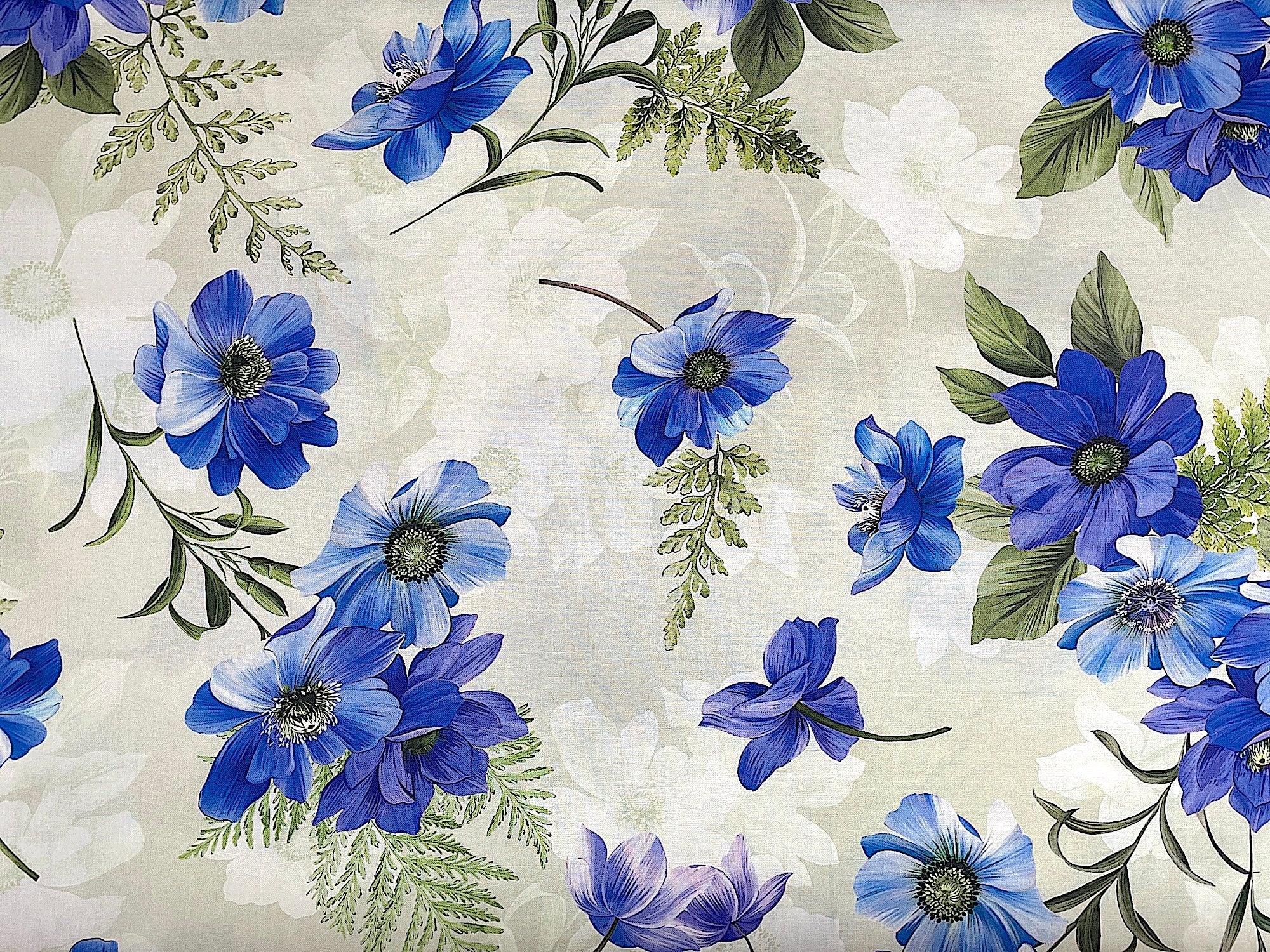This cotton fabric is covered with green ferns and flowers that are shades of blue and lavender. The background is light cream/beige. This fabric by Michael Miller is part of the Floral Fantasy collection.