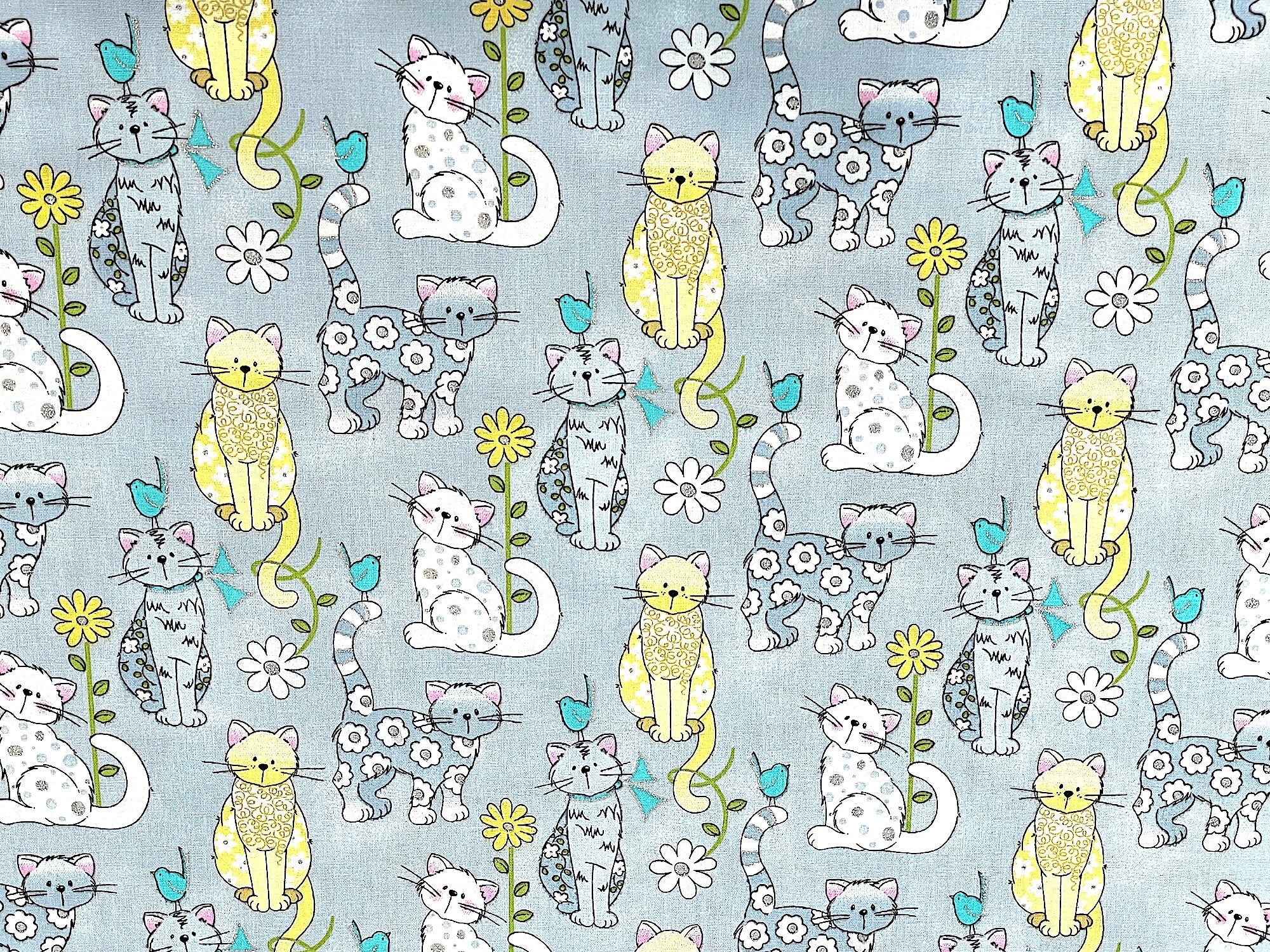 Grey, white and yellow kitties cover this cotton fabric. The kitties also have a few glitter dots on them. There are also yellow and white flowers and blue birds on this fabric.