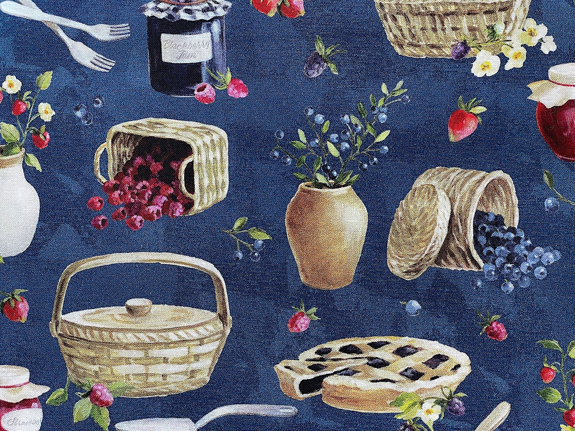 Close up of blue cotton fabric covered with pies, blueberries, raspberries and more.