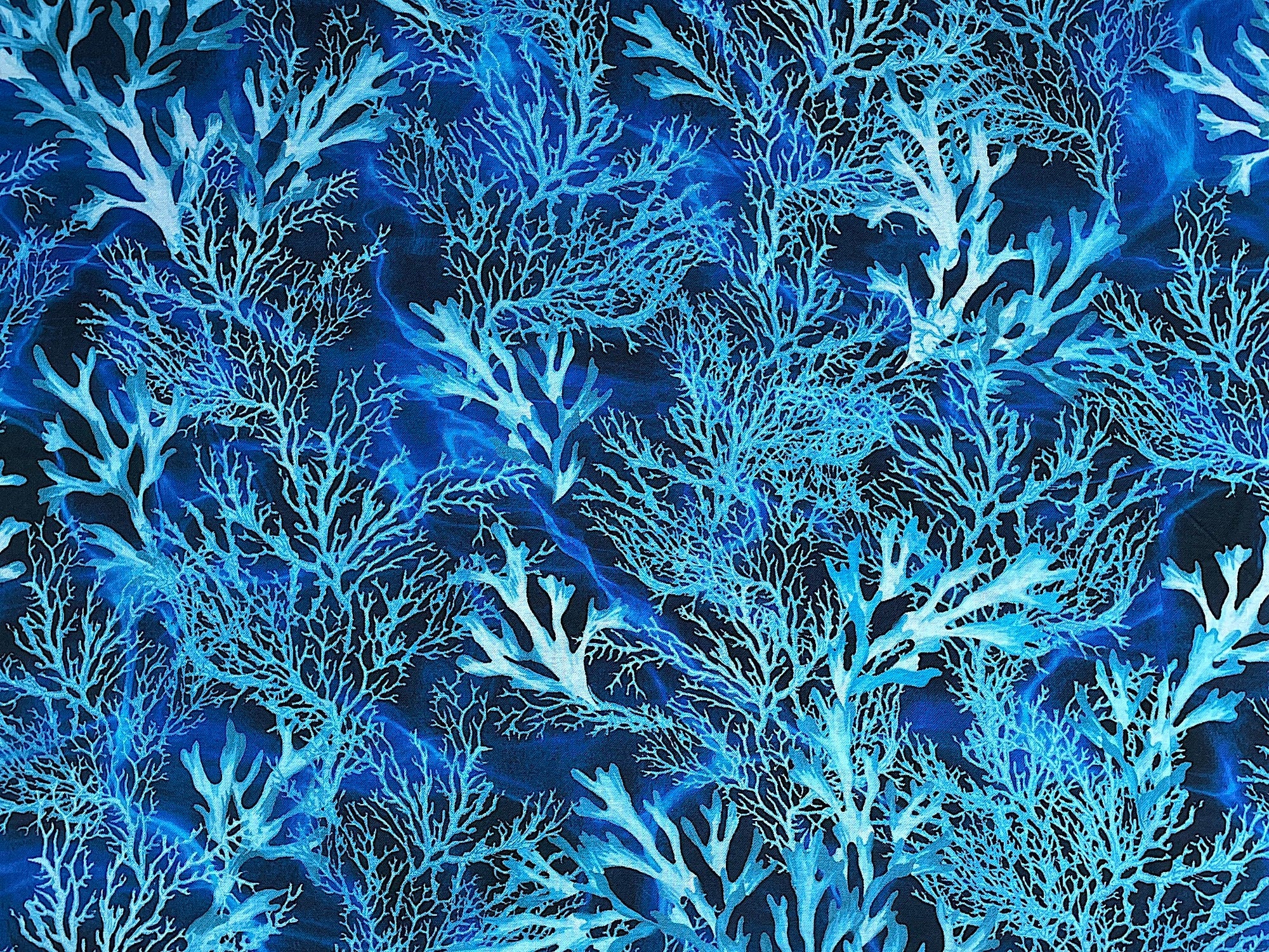 This fabric is called Coral Dance. This blue fabric is covered with coral. This fabric is part of the Oceana collection by Kanvas Studio.