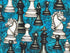Close up of white and black chess pieces on a turquoise background.