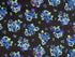 This black fabric is covered with pansies and leaves. The pansies are shades of blue and purple