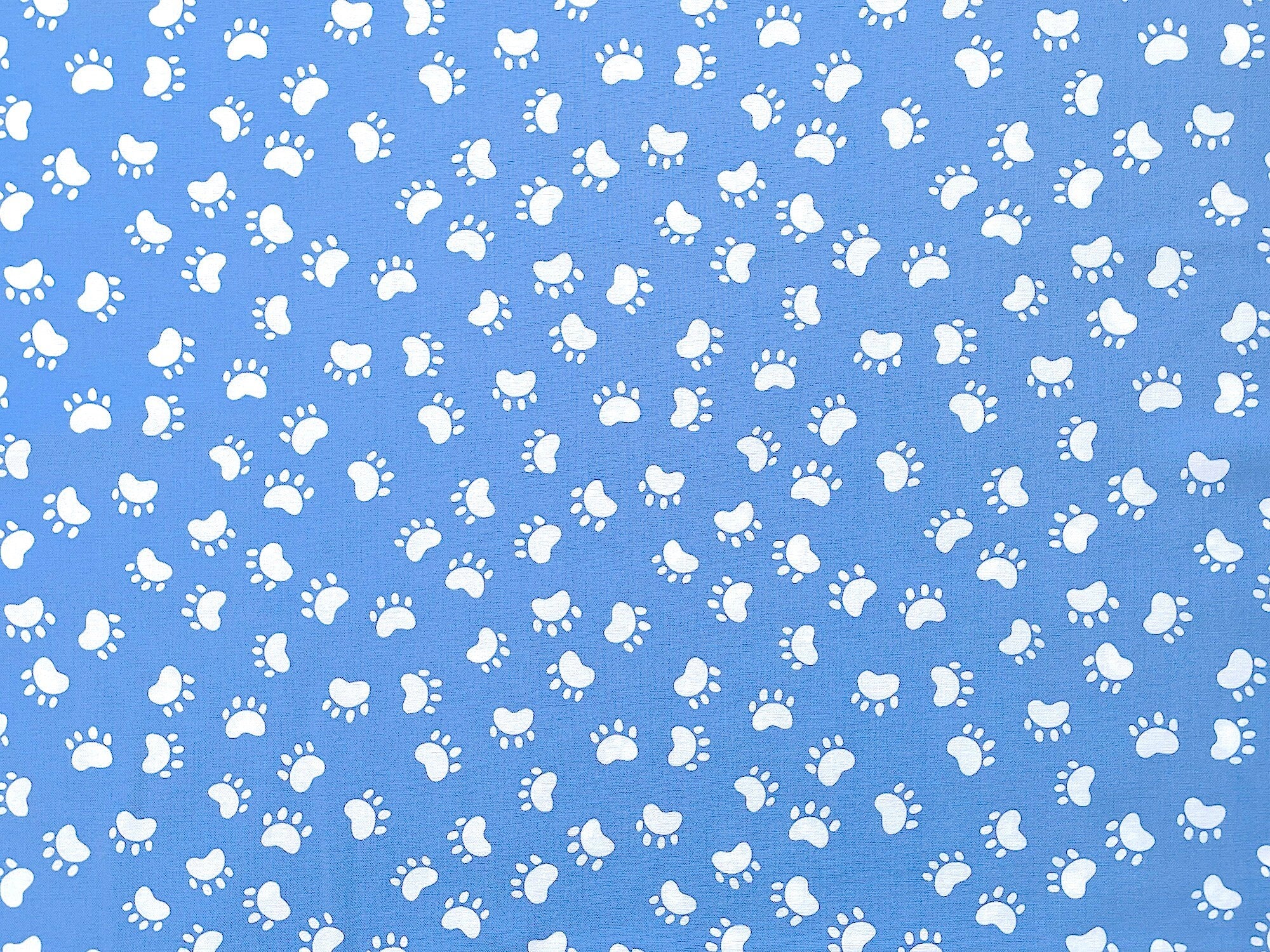 Medium blue cotton fabric covered with white paw prints.