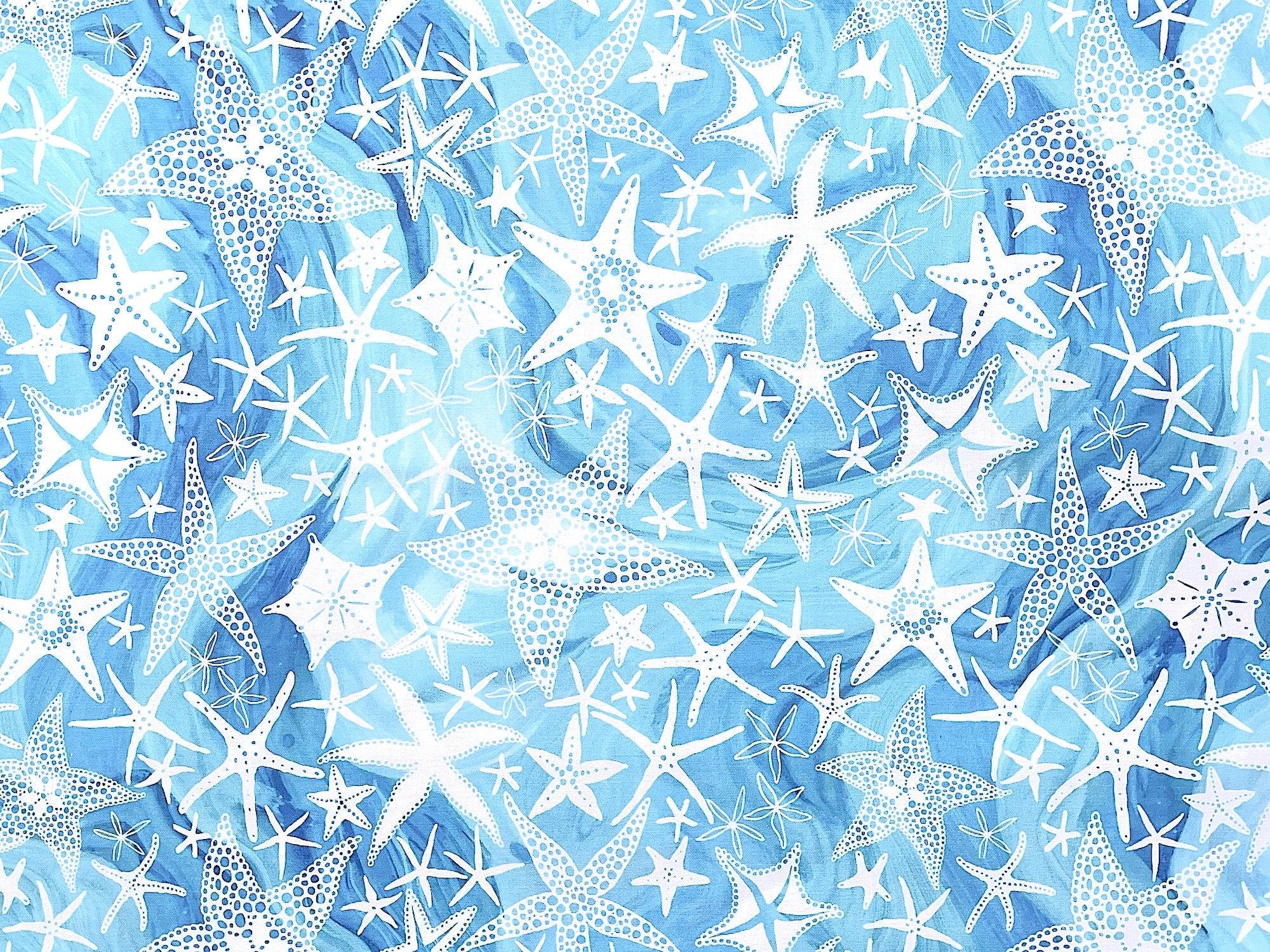 Blue fabric covered with various sizes and shaped starfish.