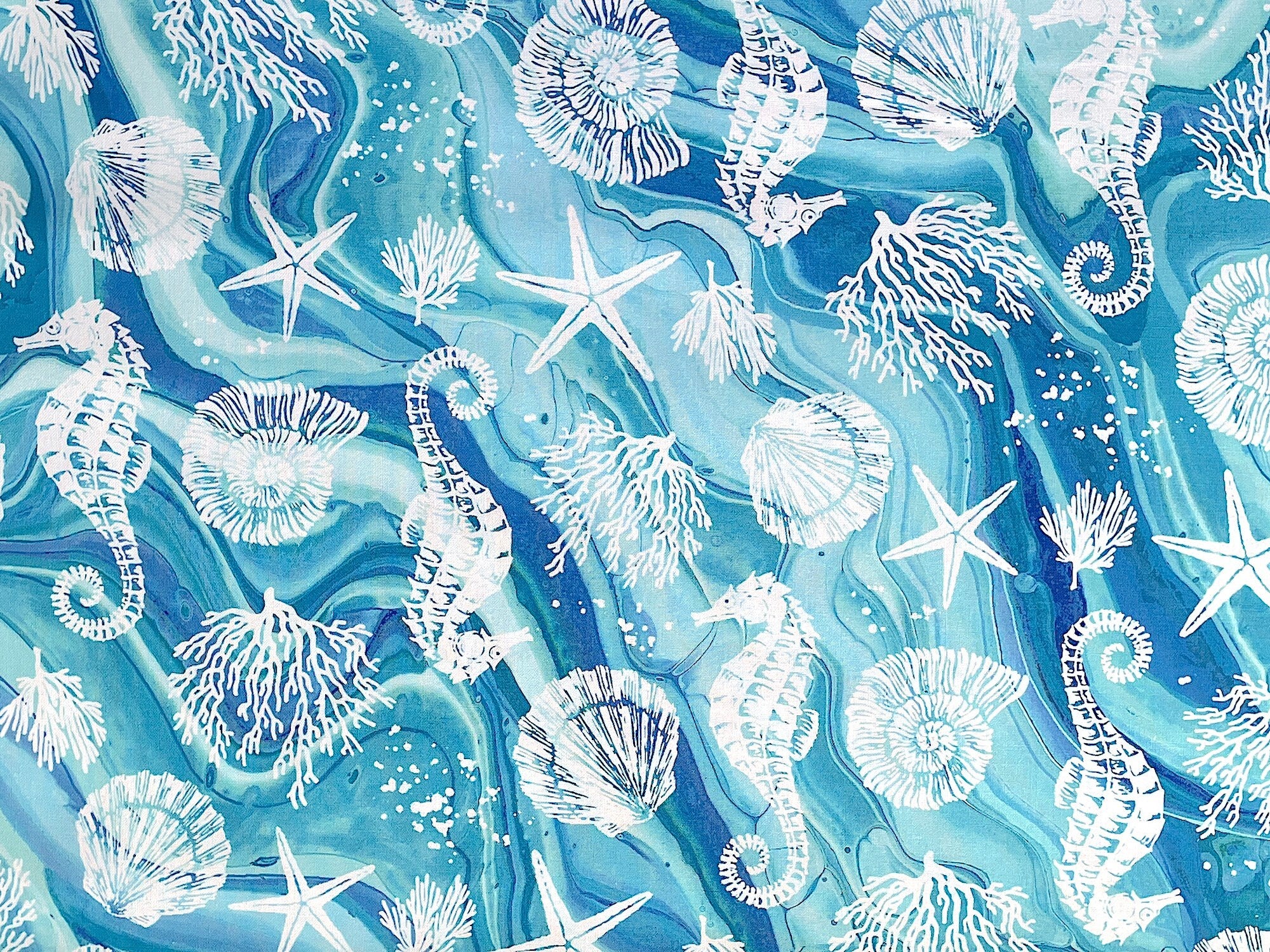 Blue cotton fabric covered with white starfish, coral and sea horses.