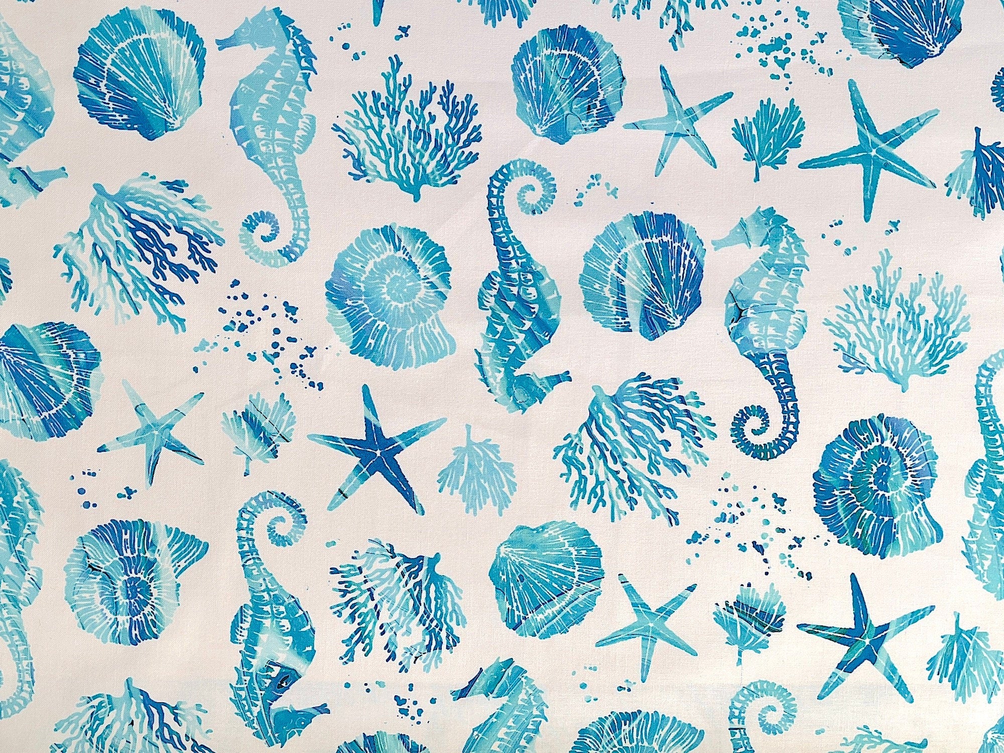 White cotton fabric covered with starfish, seahorses and sea shells.