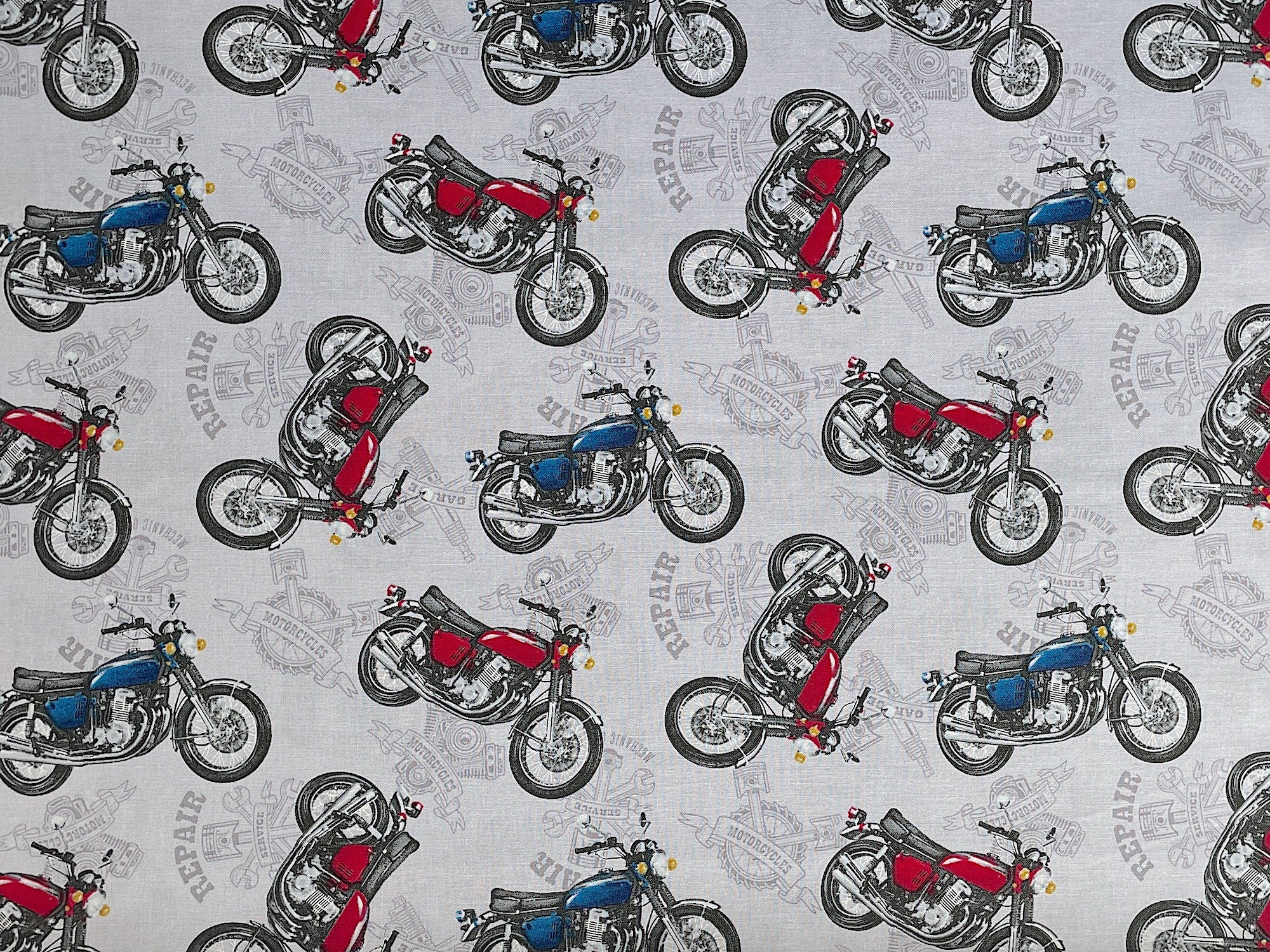 This grey fabric is part of the My Tools My Rules collection. This fabric is covered with red and blue motorcycles.