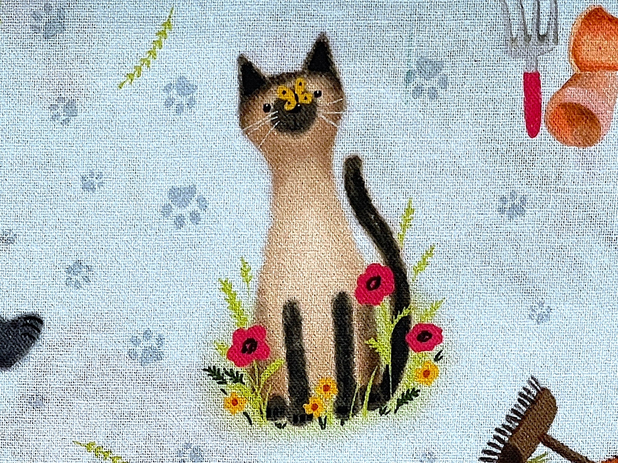 Close up of a Siamese cat sitting amongst the flowers with a butterfly on it's nose.