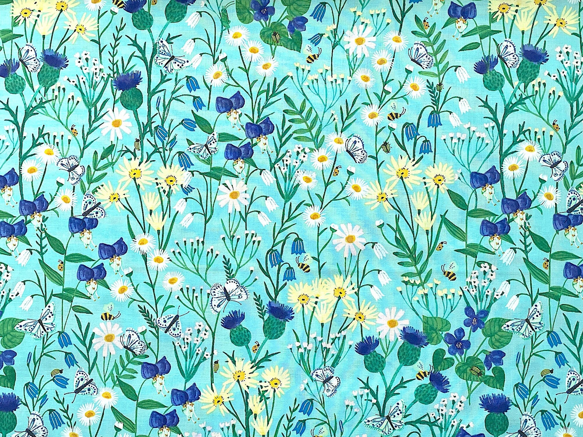 This fabric is part of the Springtime collection by Rebecca Jones. This aqua fabric is covered with white, yellow and blue flowers. There are also bees and butterflies throughout the pattern.