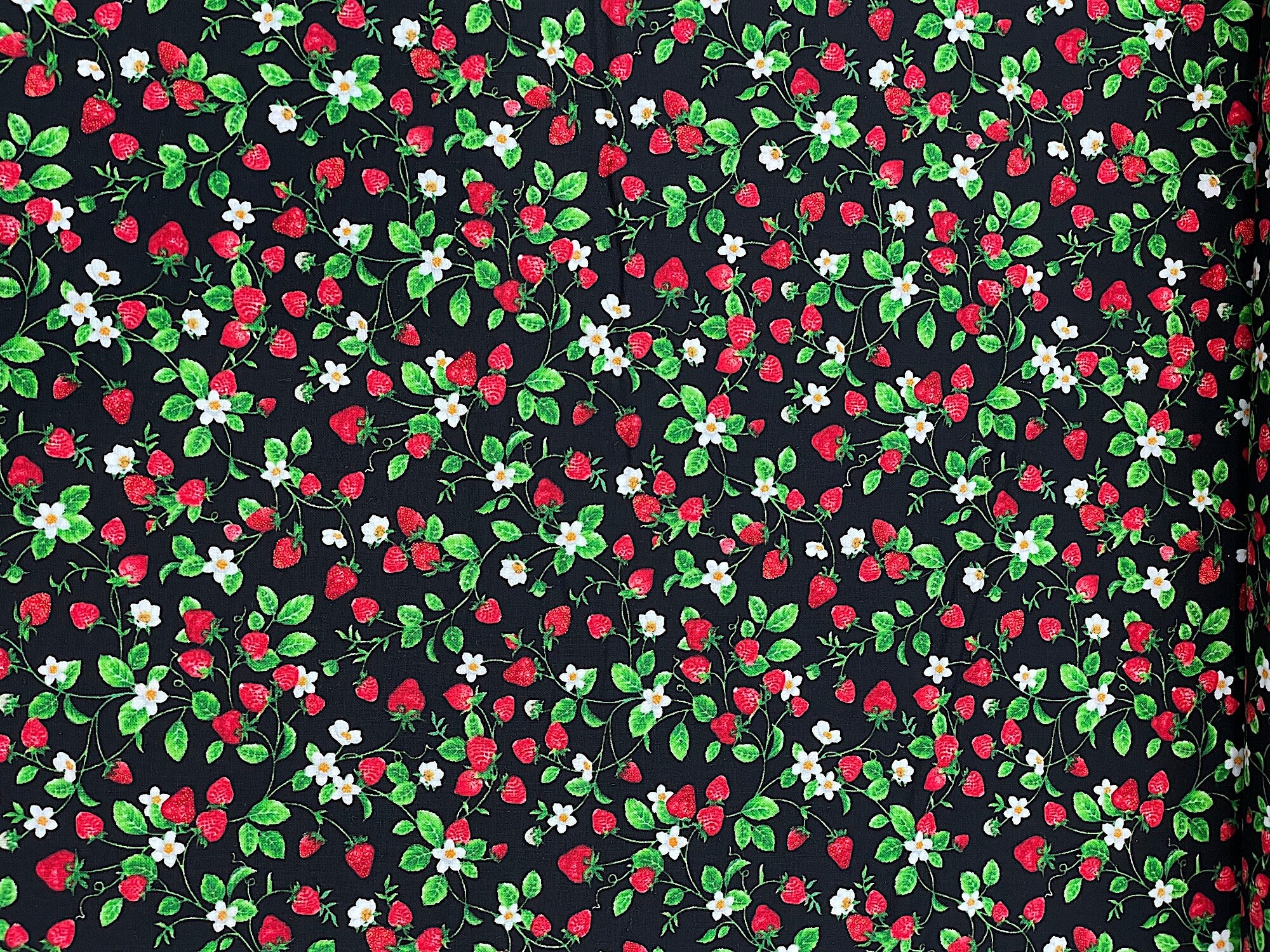 This black cotton fabric is covered with strawberries that are on the vine. There are also flowers and leaves on the vines on this strawberry fabric.