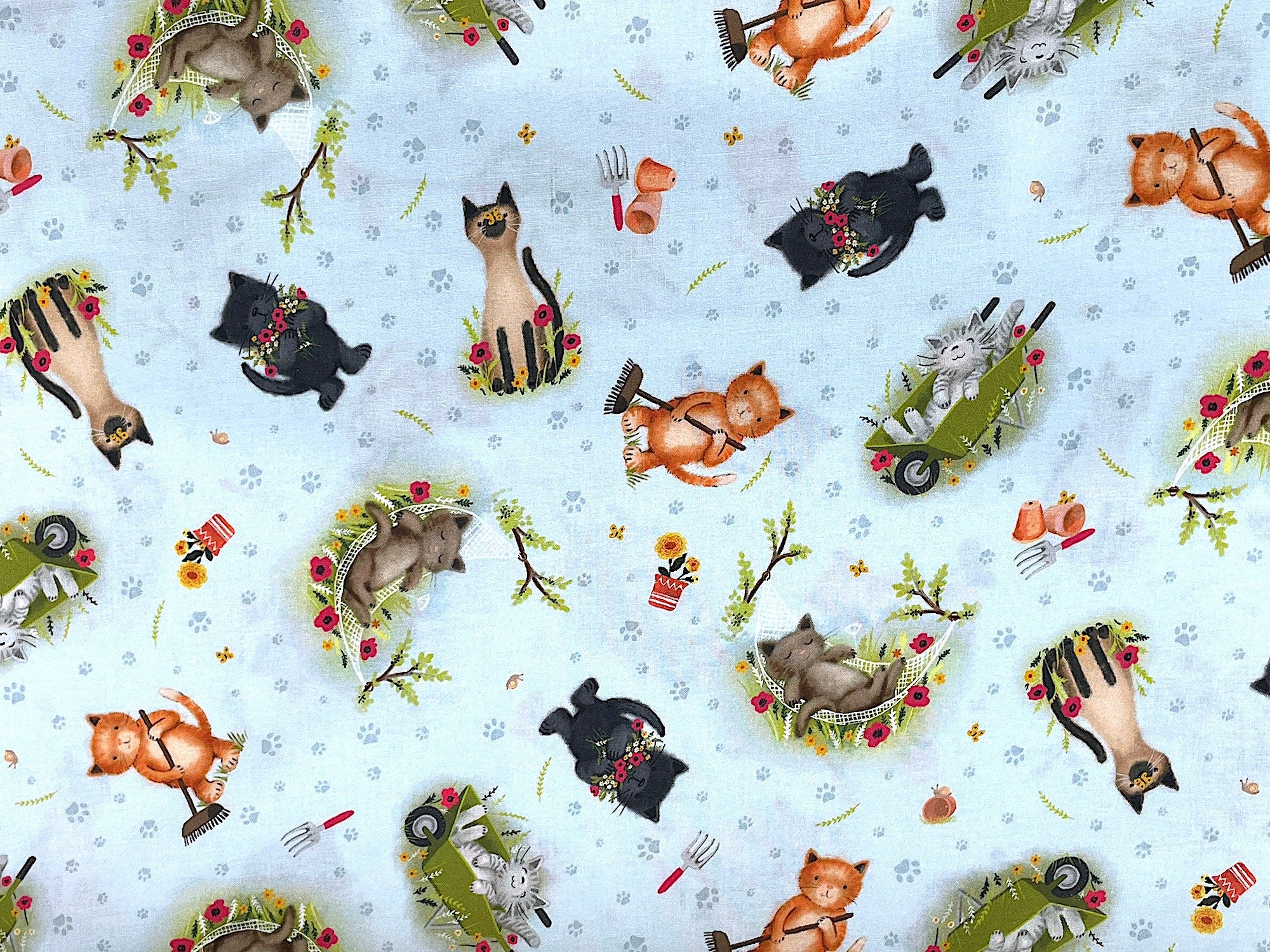 This blue/grey fabric is called Pretty Cats in the Garden and is covered with cats. Some of the cats are working in the garden, some are laying in a wheelbarrow or hammock. There are small pots of flowers and small garden hand rakes throughout the fabric. You will also find paw prints on the background.
