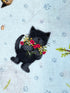 Close up of a black cat with a bunch of flowers.