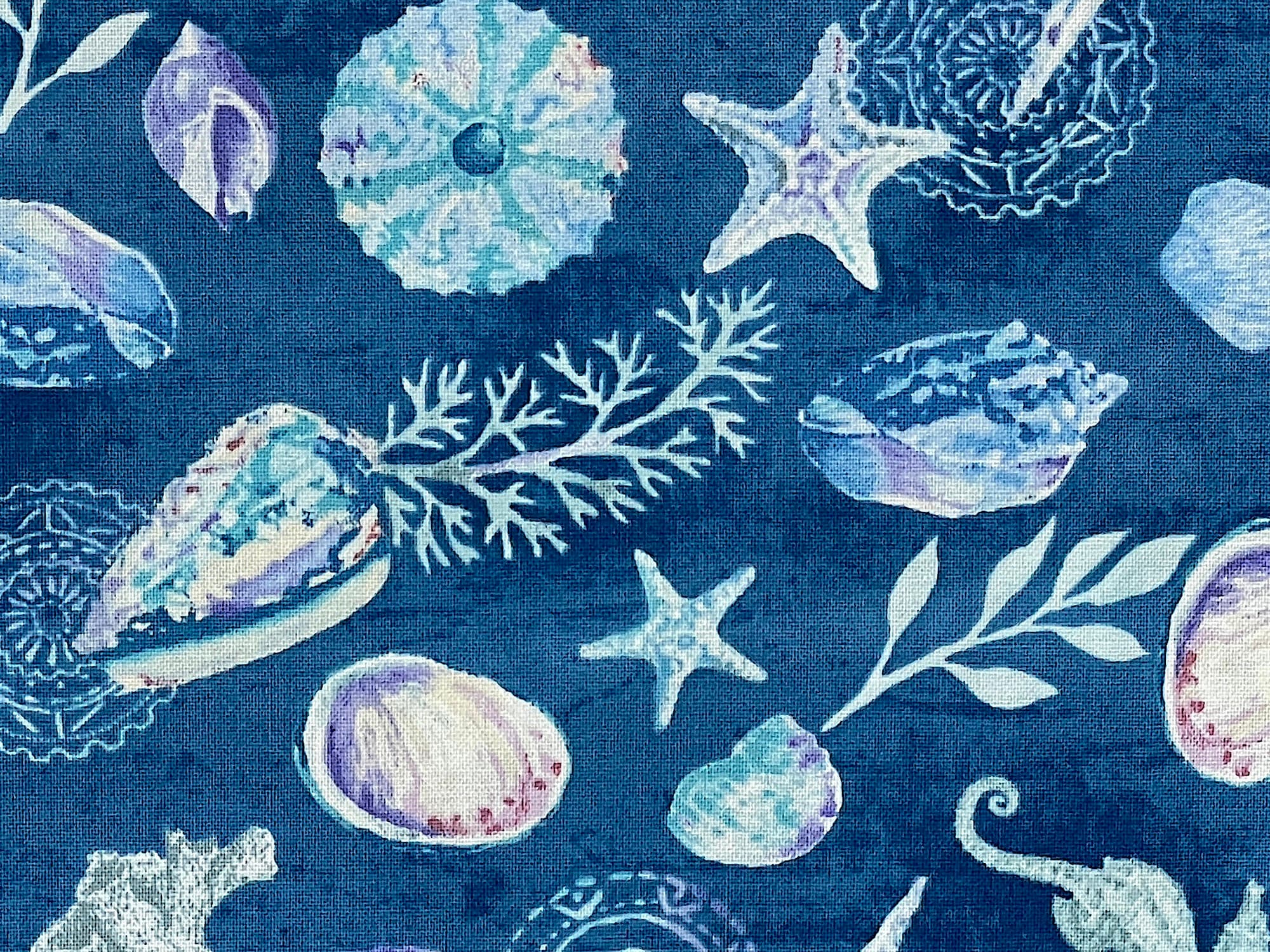 Close up of blue cotton fabric covered with seashells, starfish, plants and more.
