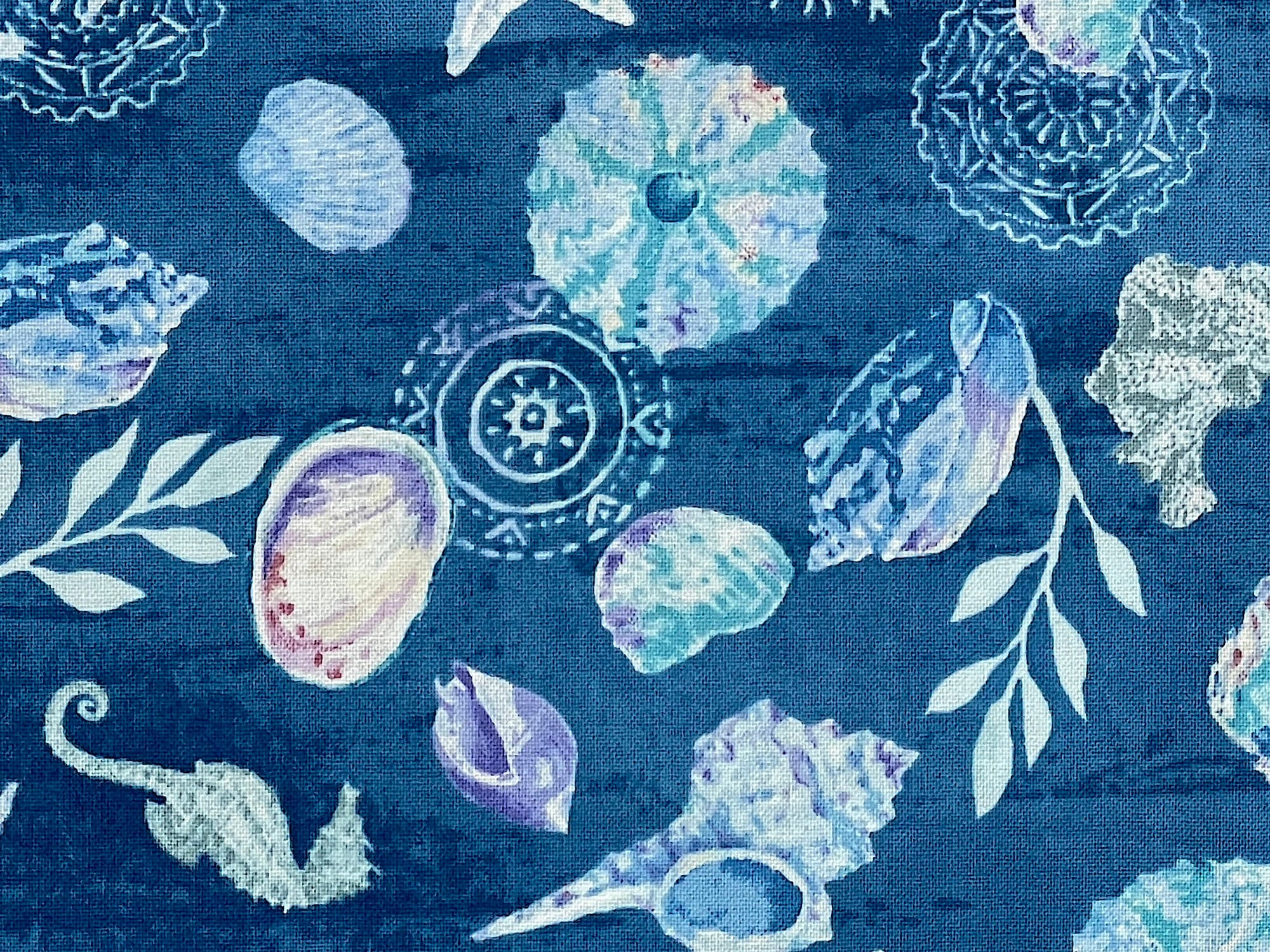 Close up of blue fabric covered with seashells and seahorses.