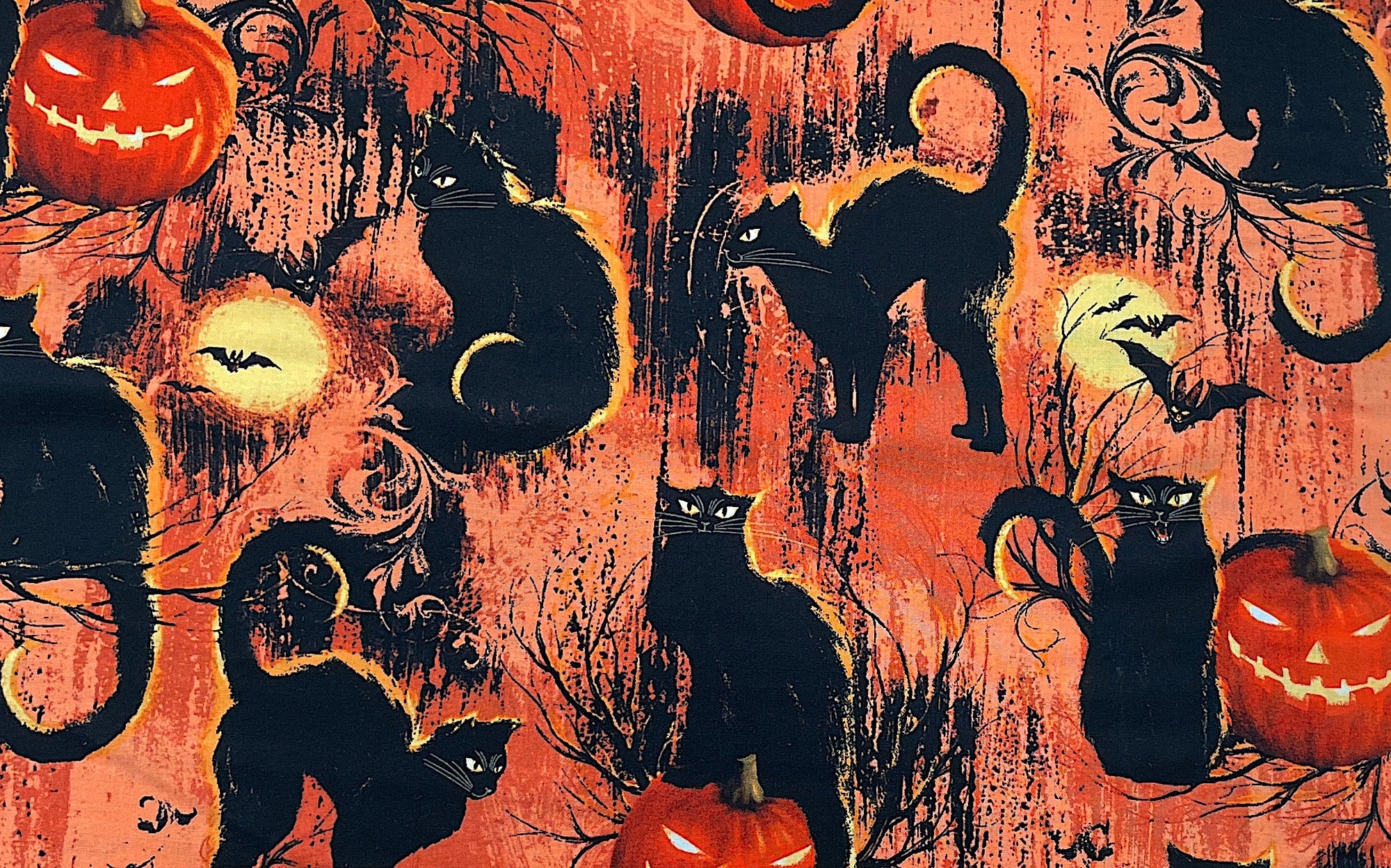 This orange fabric is covered with black cats and pumpkins. The cats are sitting on the pumpkins or on branches. There are also full moons and bats throughout the fabric.
