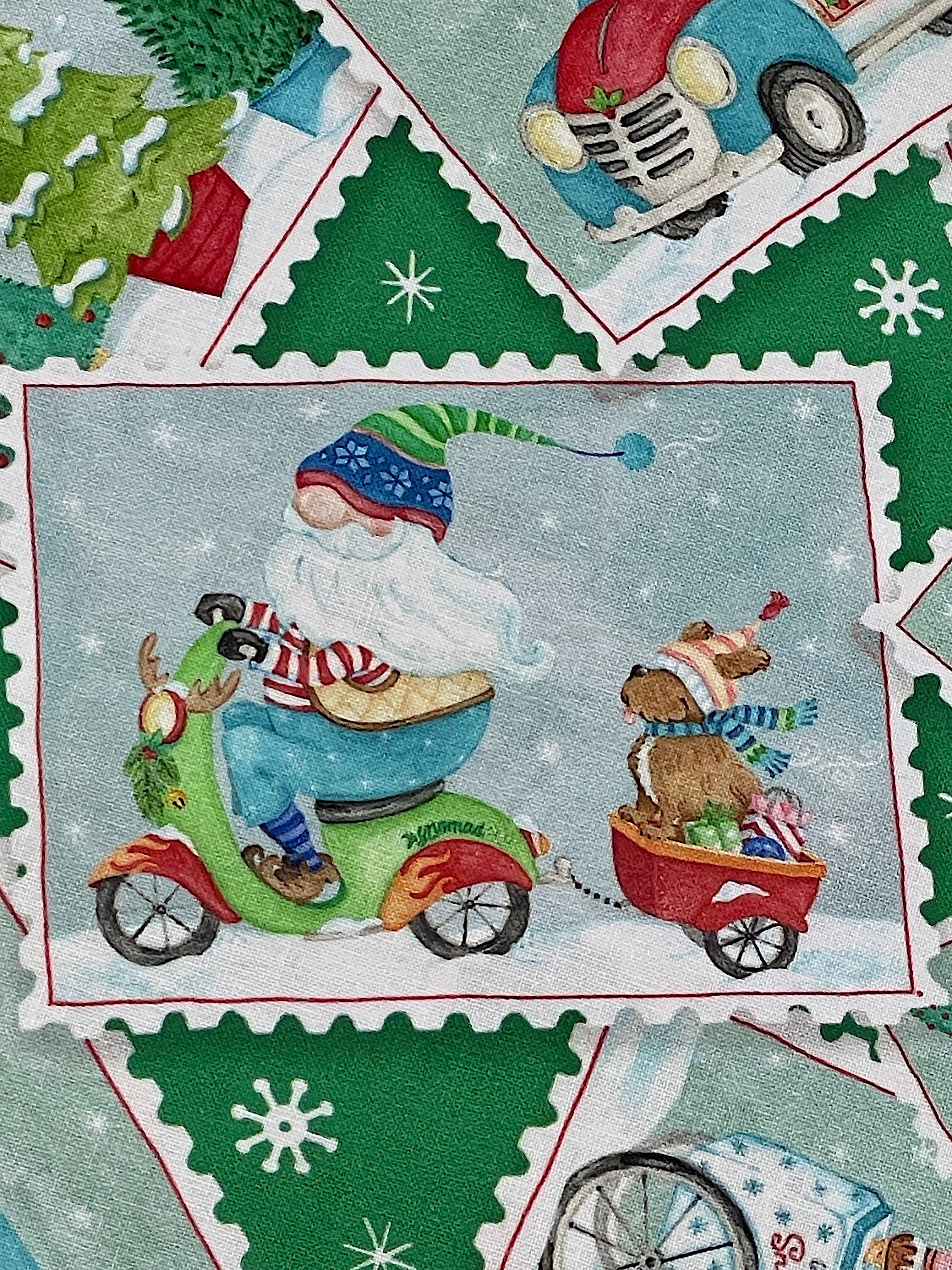 Close up of a postcard with Santa gnome riding a scooter pulling a wagon that has a dog and presents in it.