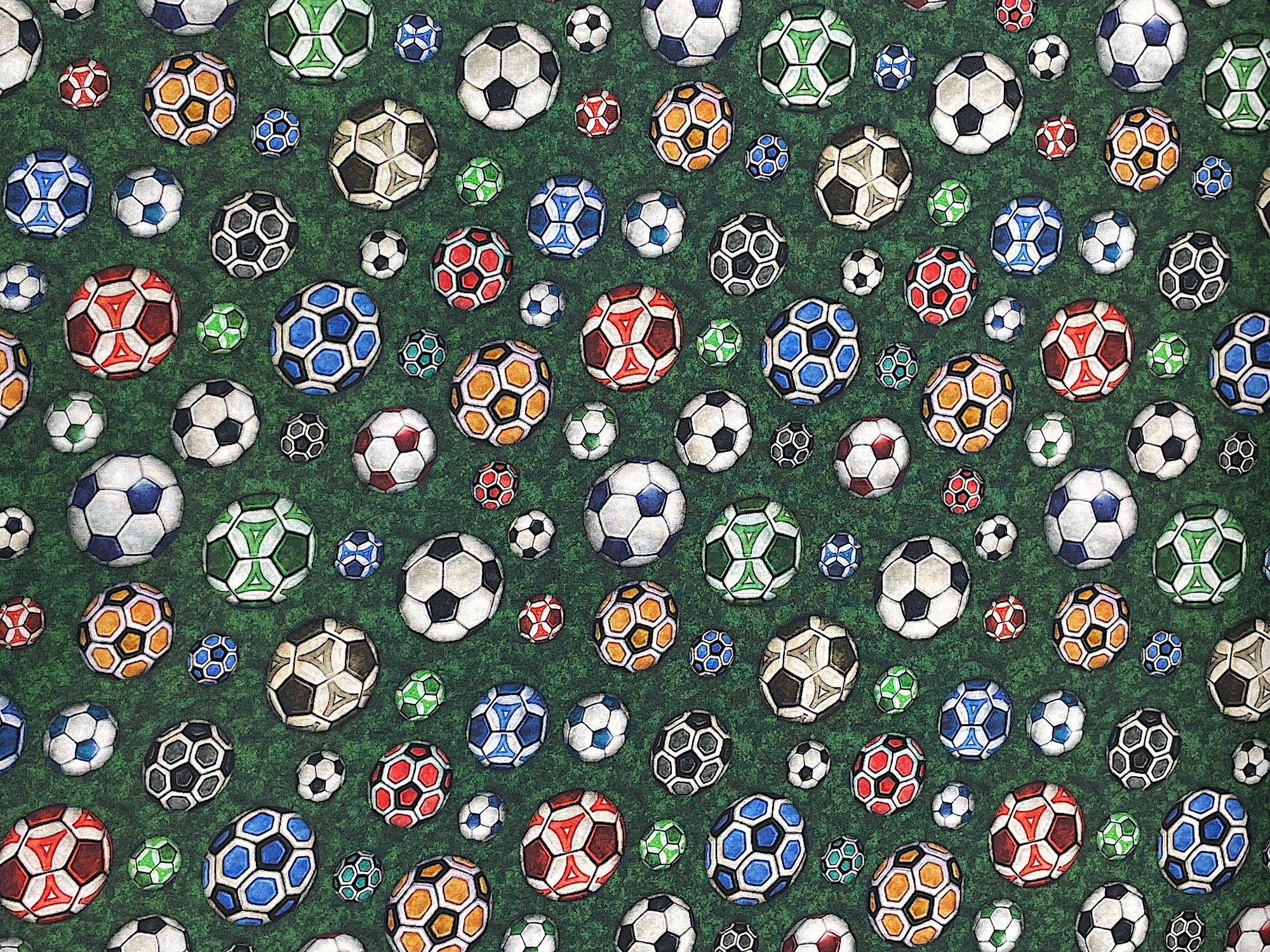 This green cotton fabric is covered with soccer balls. The soccer balls are blue, red, yellow, orange, white and black. This fabric is part of the Just For Kicks collection by QT Fabrics.